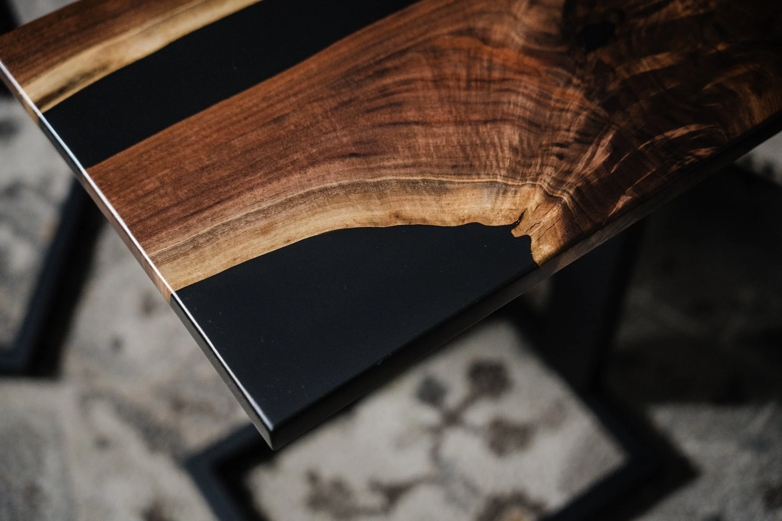 Close-up of a wooden table with a dark, glossy finish and a natural wood grain pattern, with some chipped edges.