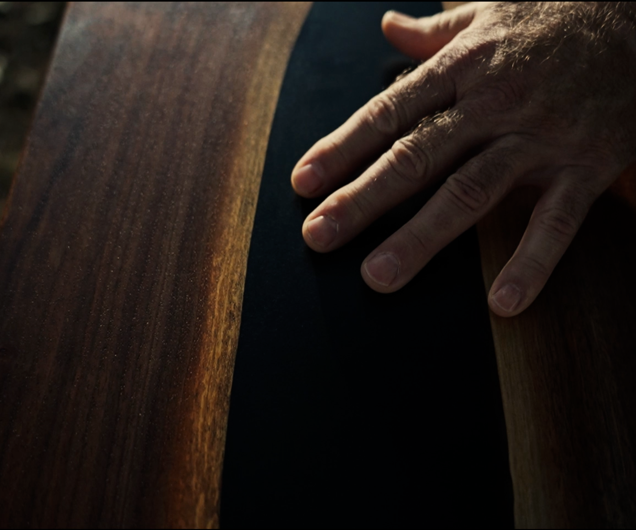 A person's hand resting on a wooden surface.