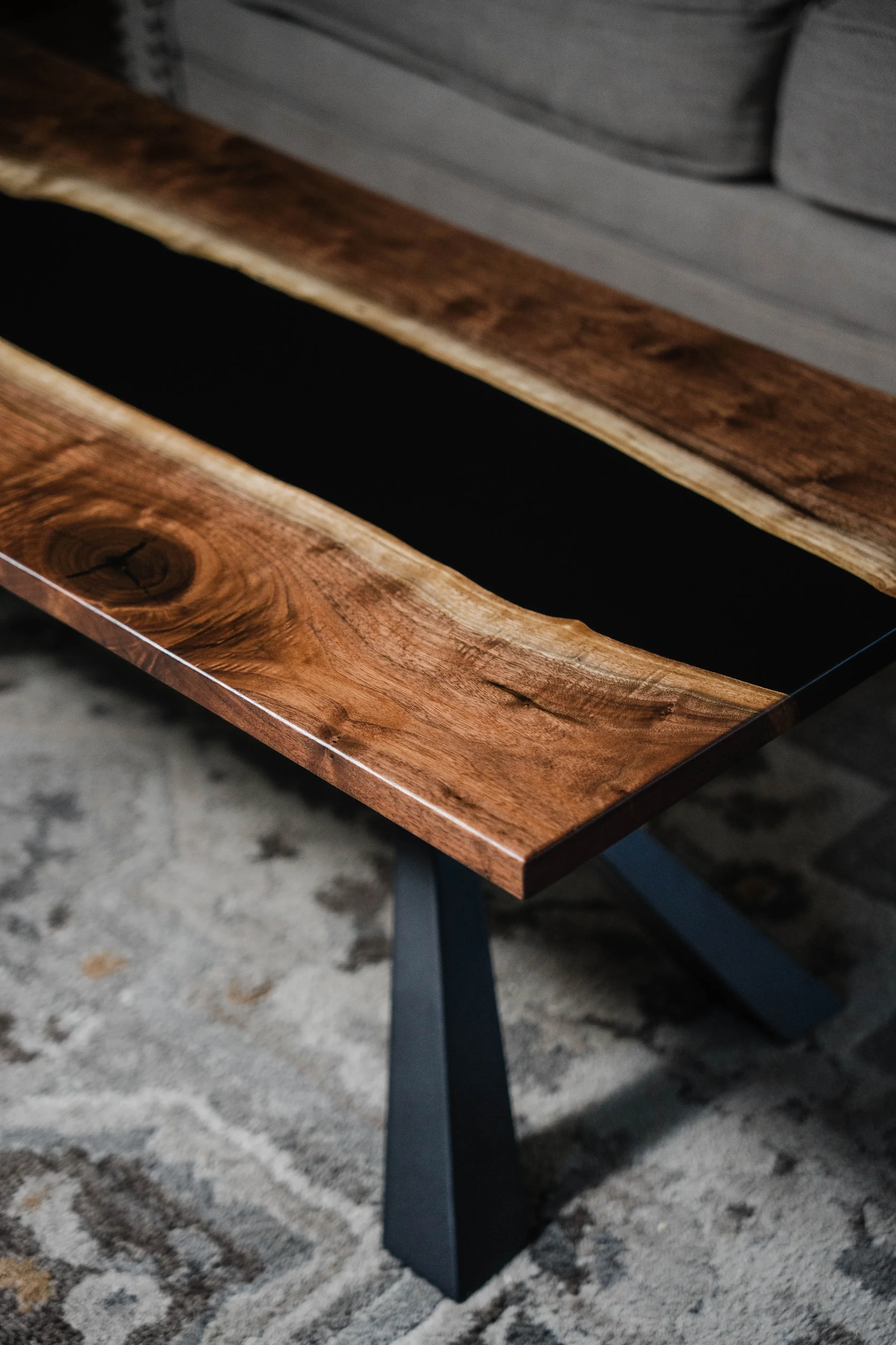 A wooden table with a dark inlay and metal legs, placed on a patterned rug.