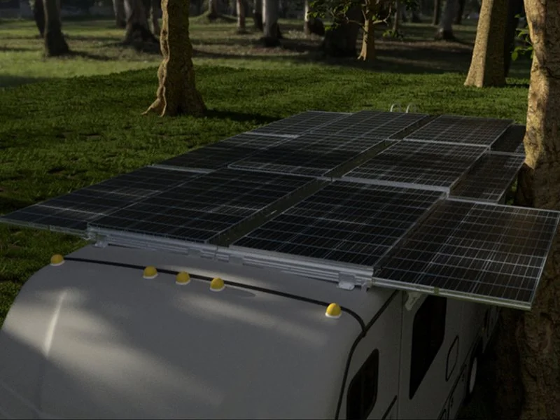 Solar panels installed on the roof of a white RV in a park with trees.