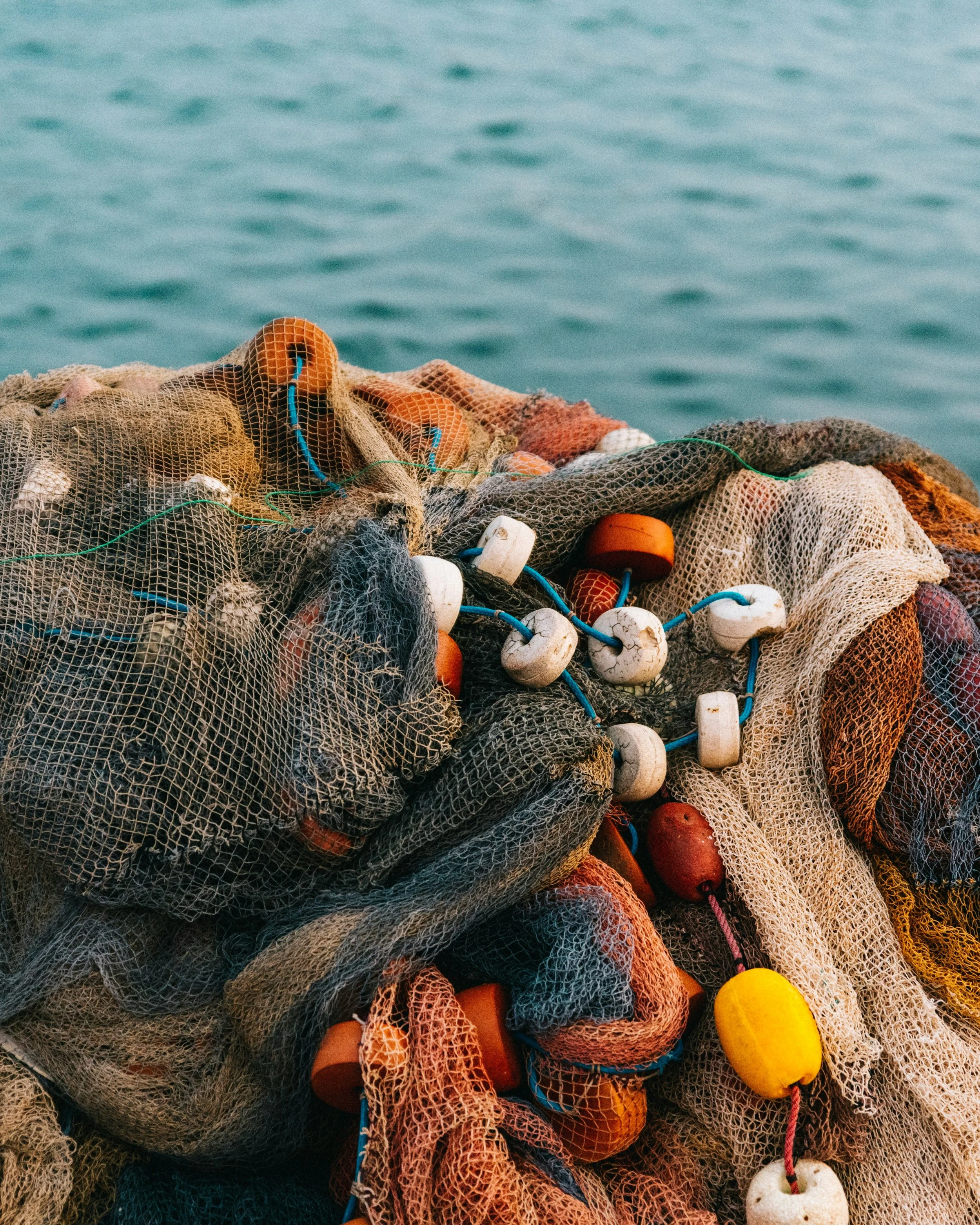 A pile of fishing nets with colorful floats floating on the water.