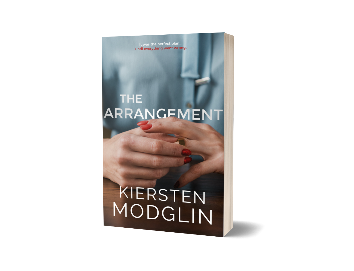 Book titled 'The Arrangement' by Kiersten Modglin with a cover image of hands with red nail polish holding a gold ring, against a light blue shirt background.