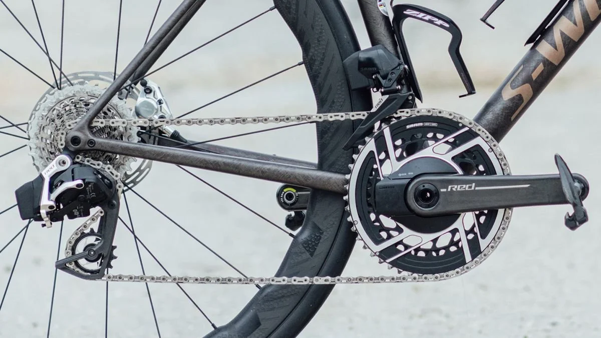 Close-up of a modern bicycle's rear drivetrain, including the derailleur, chain, cassette, crankset, and pedal.