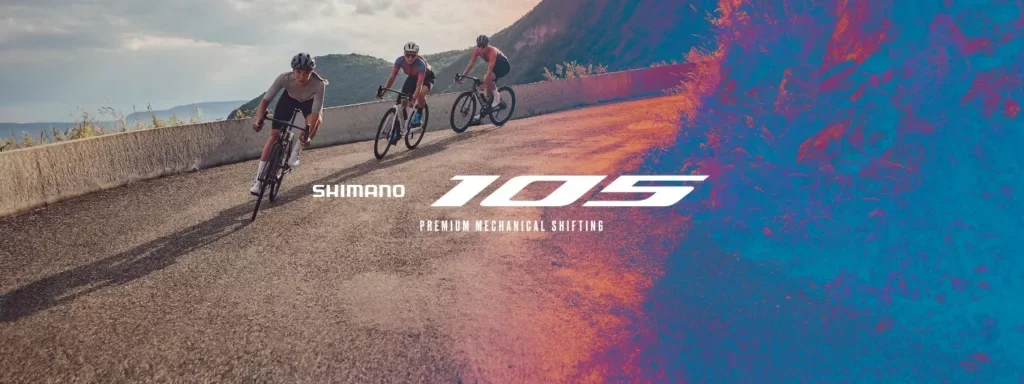 Three cyclists riding on a curved outdoor mountain road with mountains in the background, overlaid with the Shimano 105 logo and the text "Premium Mechanical Shifting."