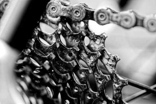 Close-up of a bicycle's gear cassette and chain, showing the gears and chain links.