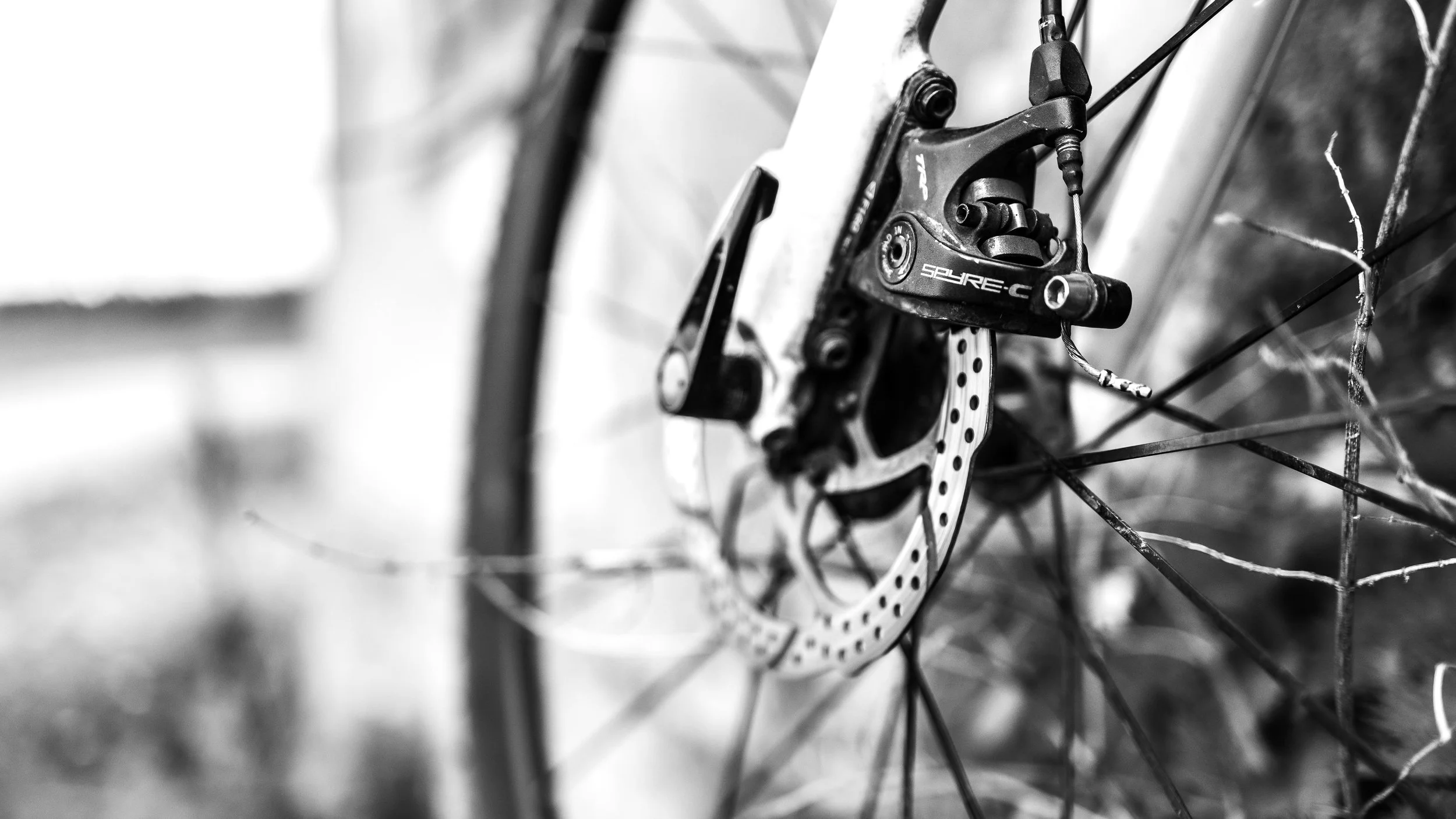 Close-up of a bicycle disc brake and rotor attached to the wheel, black and white photo.