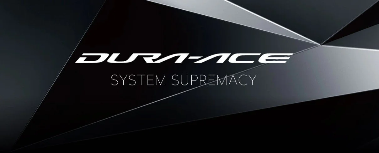 Close-up of the Dura-Ace logo and the words 'System Supremacy' on a black and gray background.