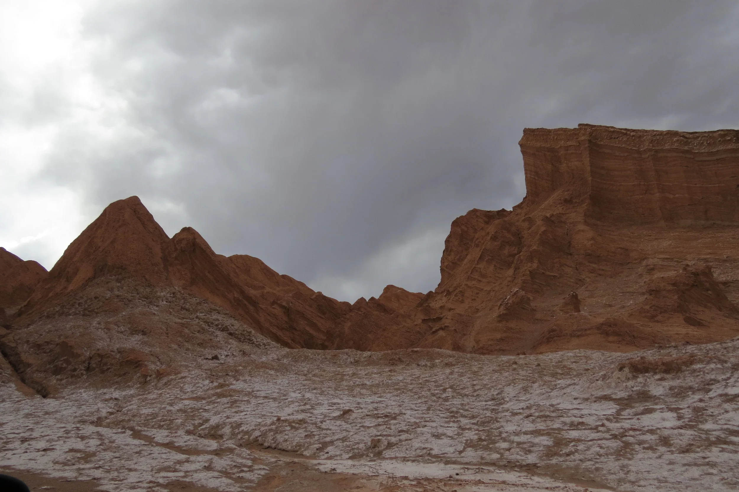 Red rock formations under a cloudy sky in a desert landscape.