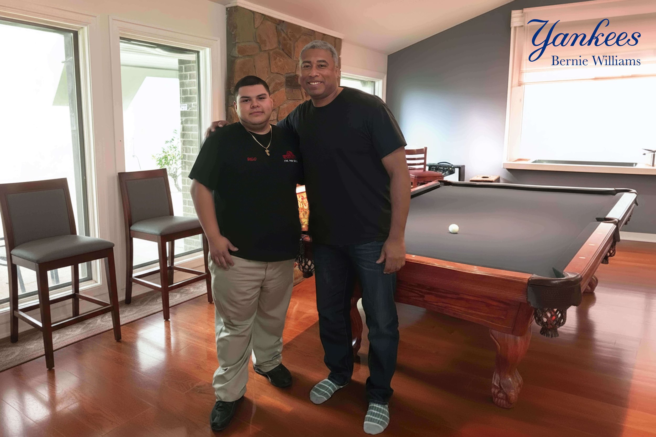 Two men standing next to each other in a room with a pool table. The man on the left is younger, wearing a black shirt, beige pants, and black shoes. The man on the right is older, wearing a black t-shirt, jeans, and gray striped slippers. There are 