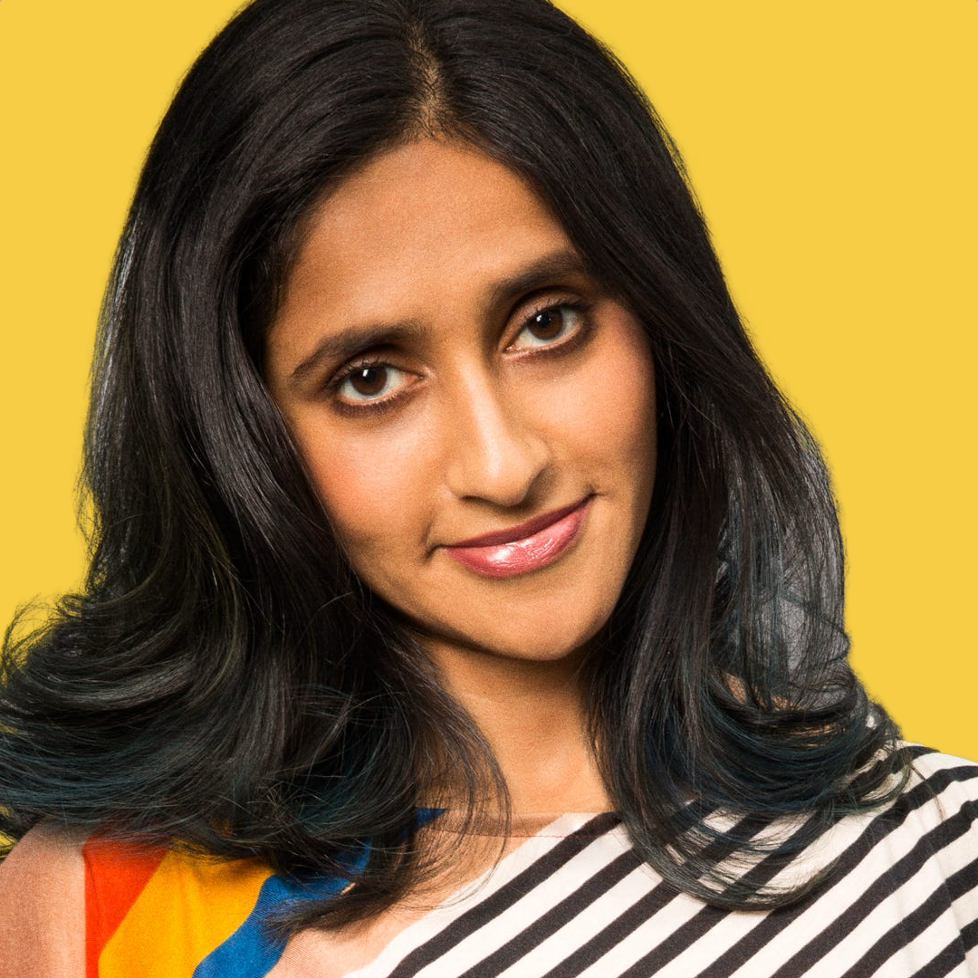 Close-up of a woman with dark hair, wearing a striped top, smiling against a yellow background.