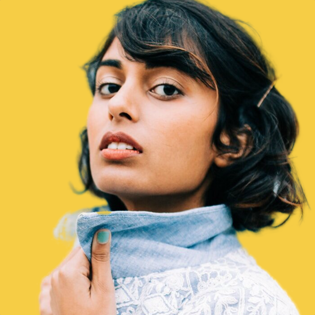 Portrait of a young woman with dark, wavy hair and light makeup, wearing a light-colored, embroidered blouse against a bright yellow background.