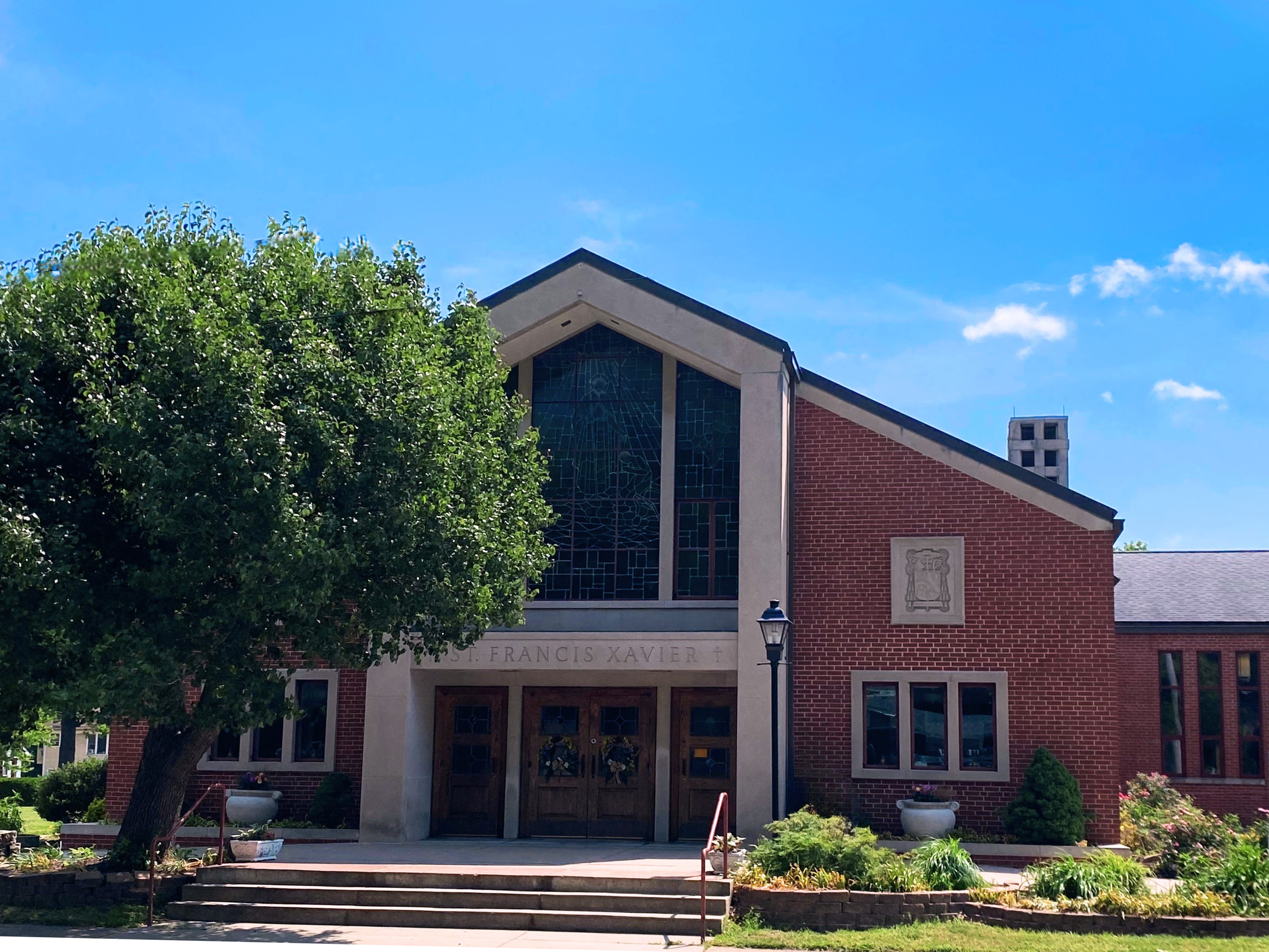 Saint Francis Xavier Church - red brick church with stained glass windows and greenery in front