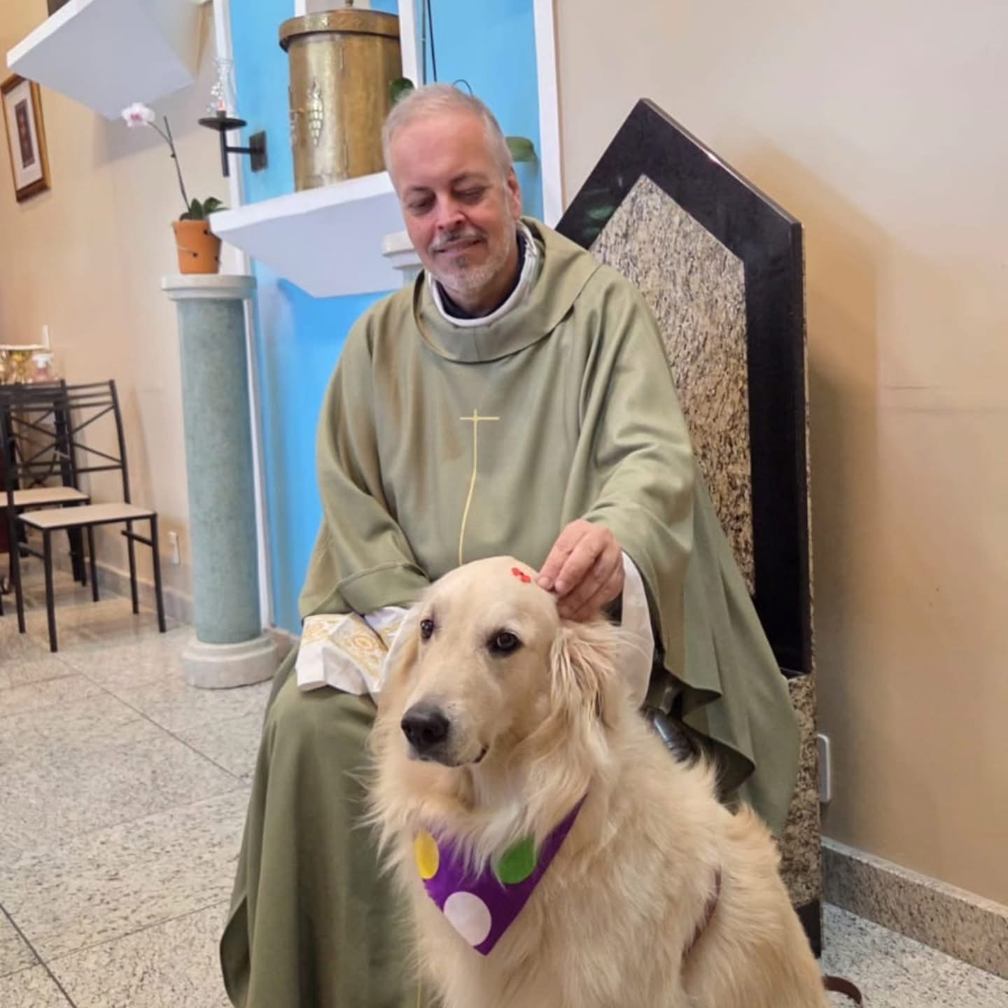A priest pets the head of a golden retriever