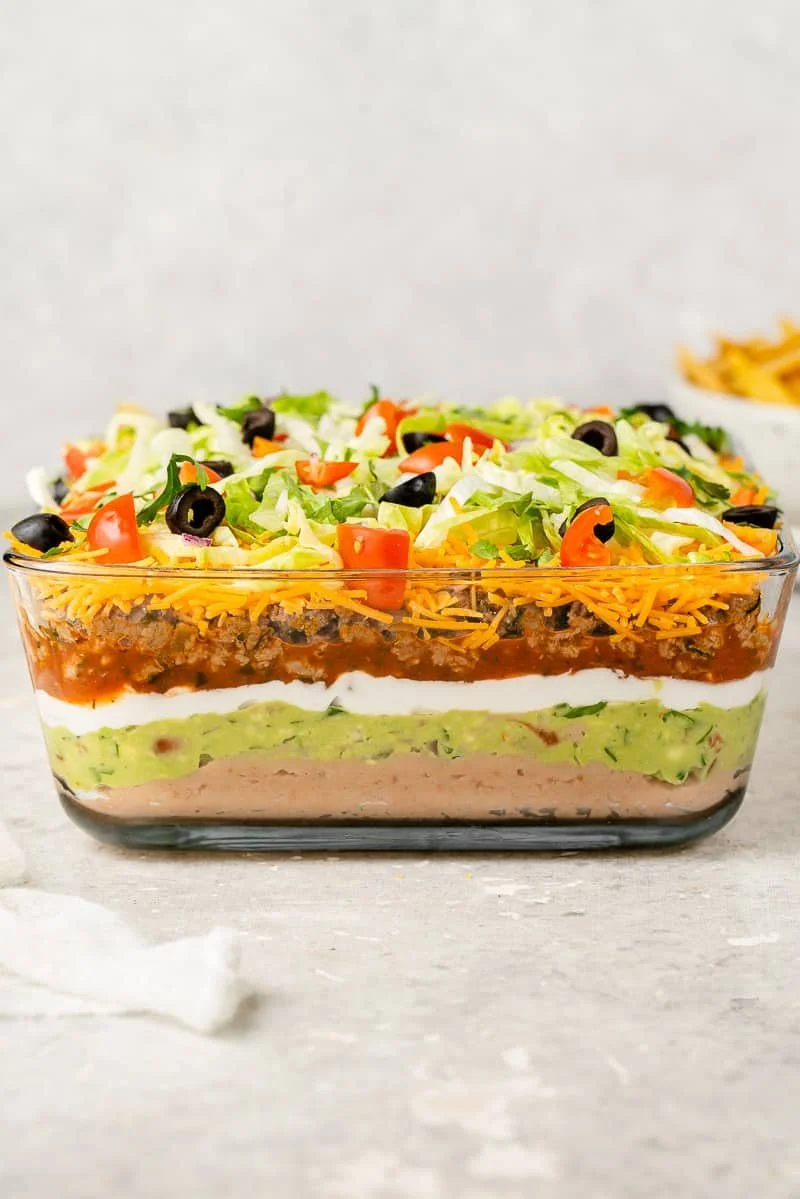 7-Layer Dip with beans, guacamole, vegan sour cream, vegan cheese, salsa, lettuce, black olives, and chopped tomatoes