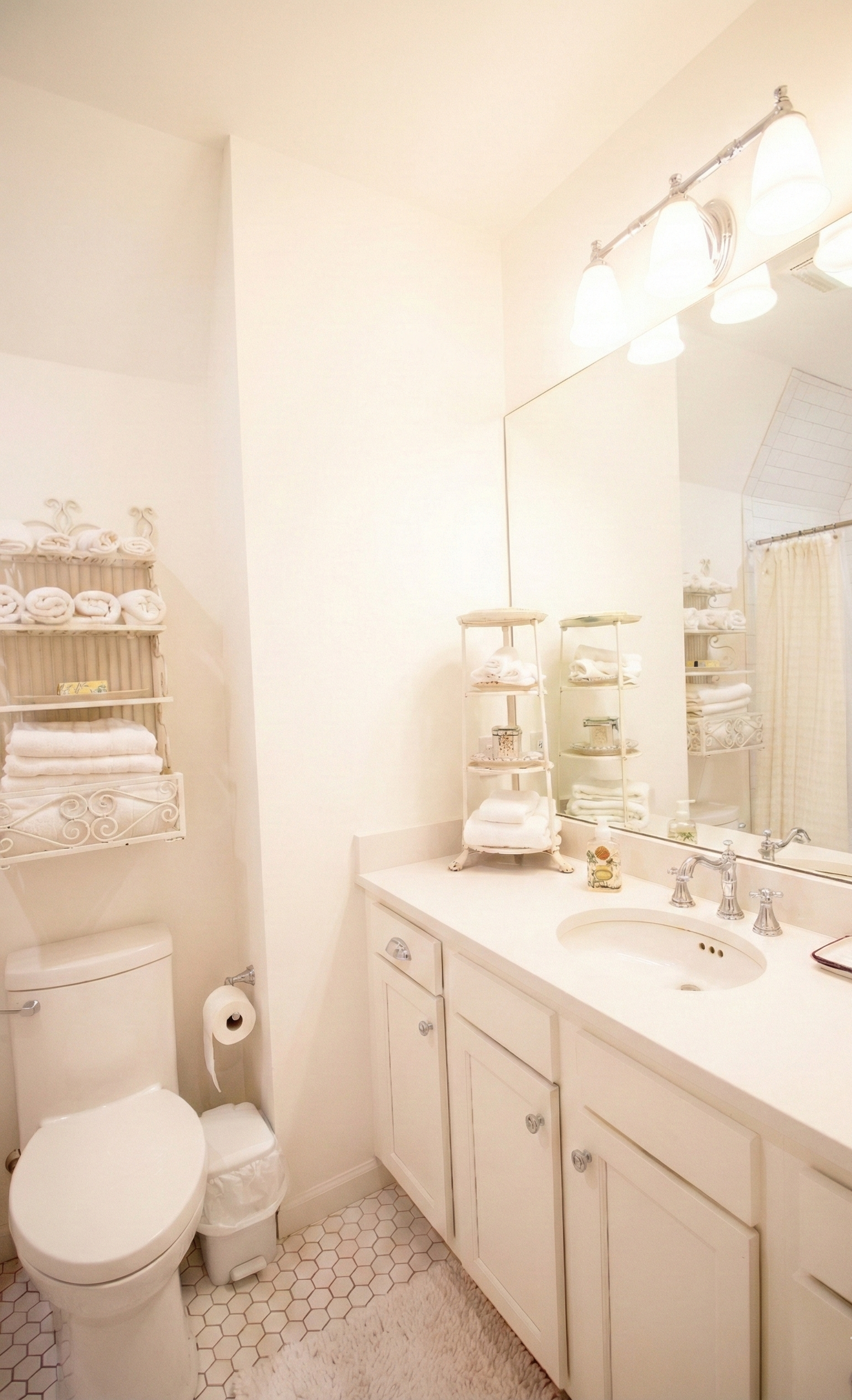 A small bathroom with a white toilet, white vanity with a mirror, and shelves with towels and toiletries.