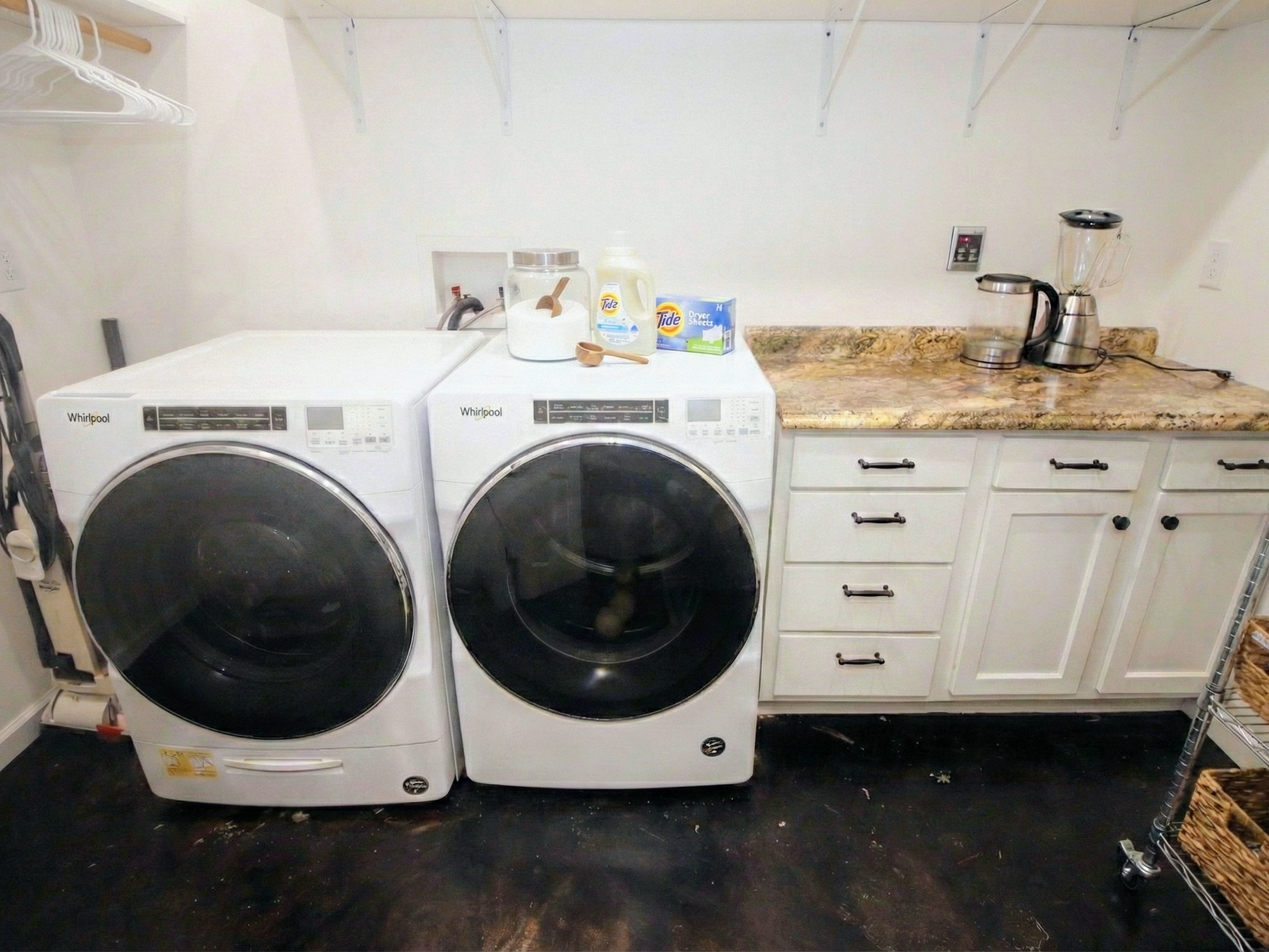 Laundry room with washer and dryer, a countertop, and shelves with kitchen appliances and supplies.