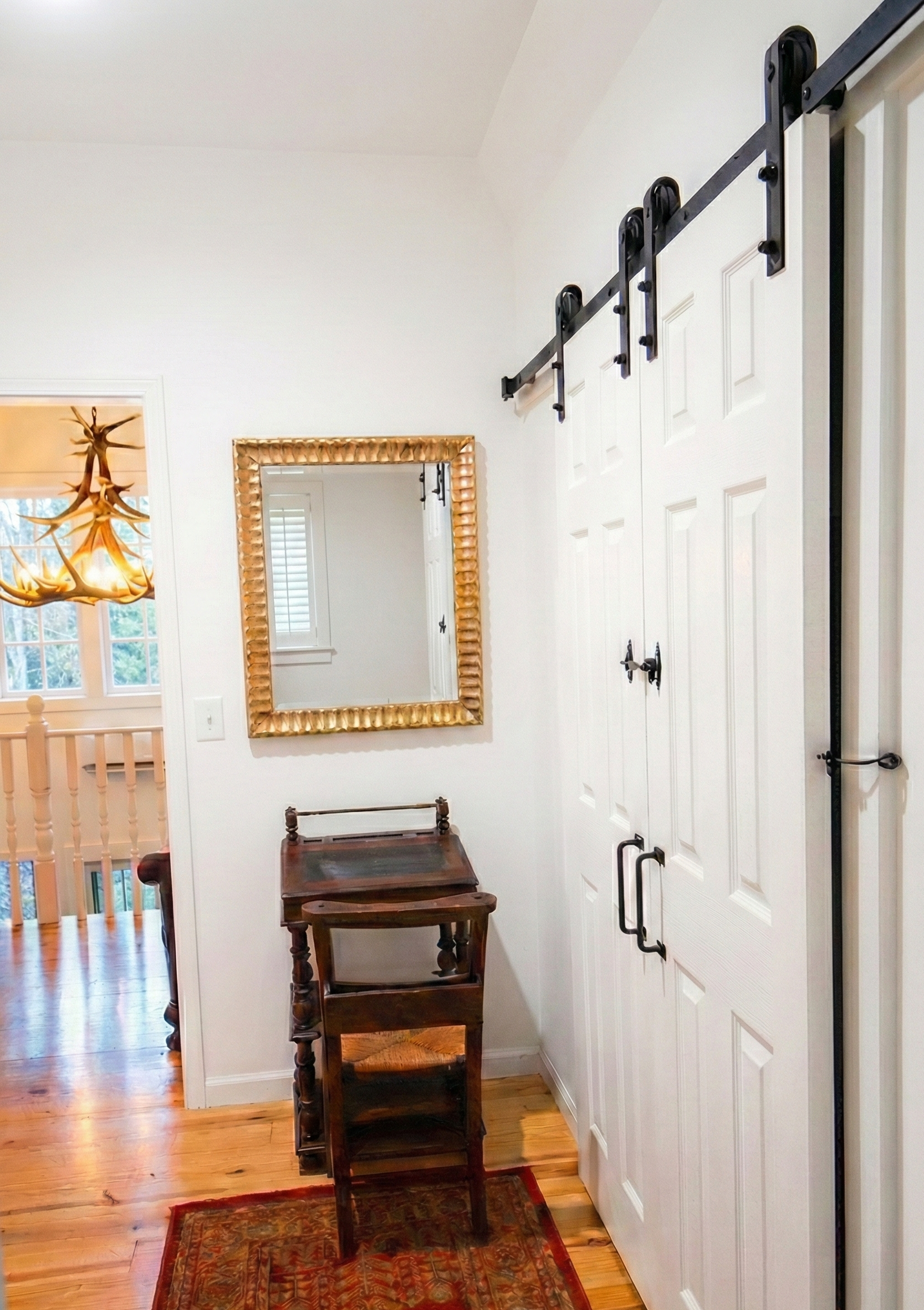 Entryway with a mirror, a wooden table, and a sliding barn door on a hallway wall.