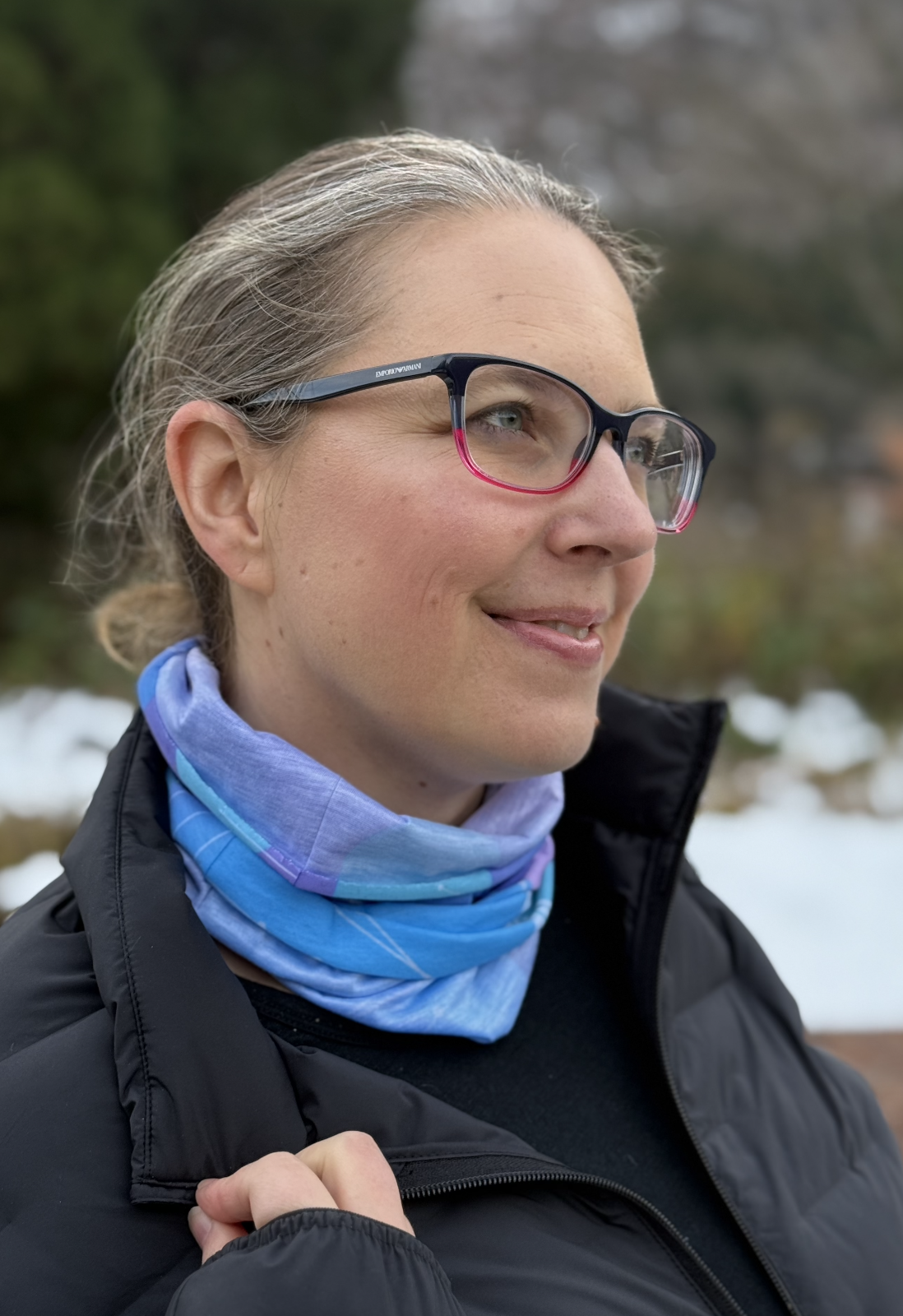 Female wears purple and blue tube scarf gathered around neck.