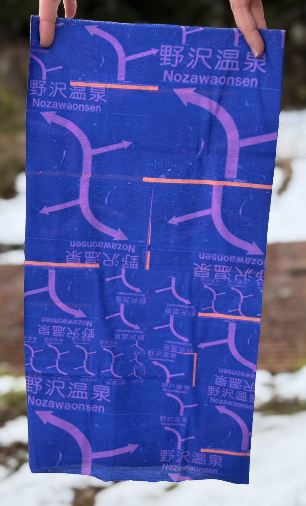 Product image of a purple and pink rectangle ski scarf with a collage of the sign at the top of the Nozawa Onsen gondola.