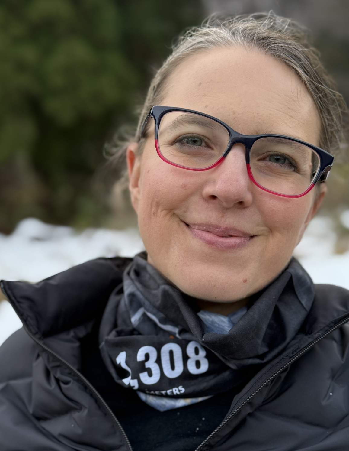 Black, orange, and white tube scarf bunched up around a females neck. Visible part reads 1,308 meters.