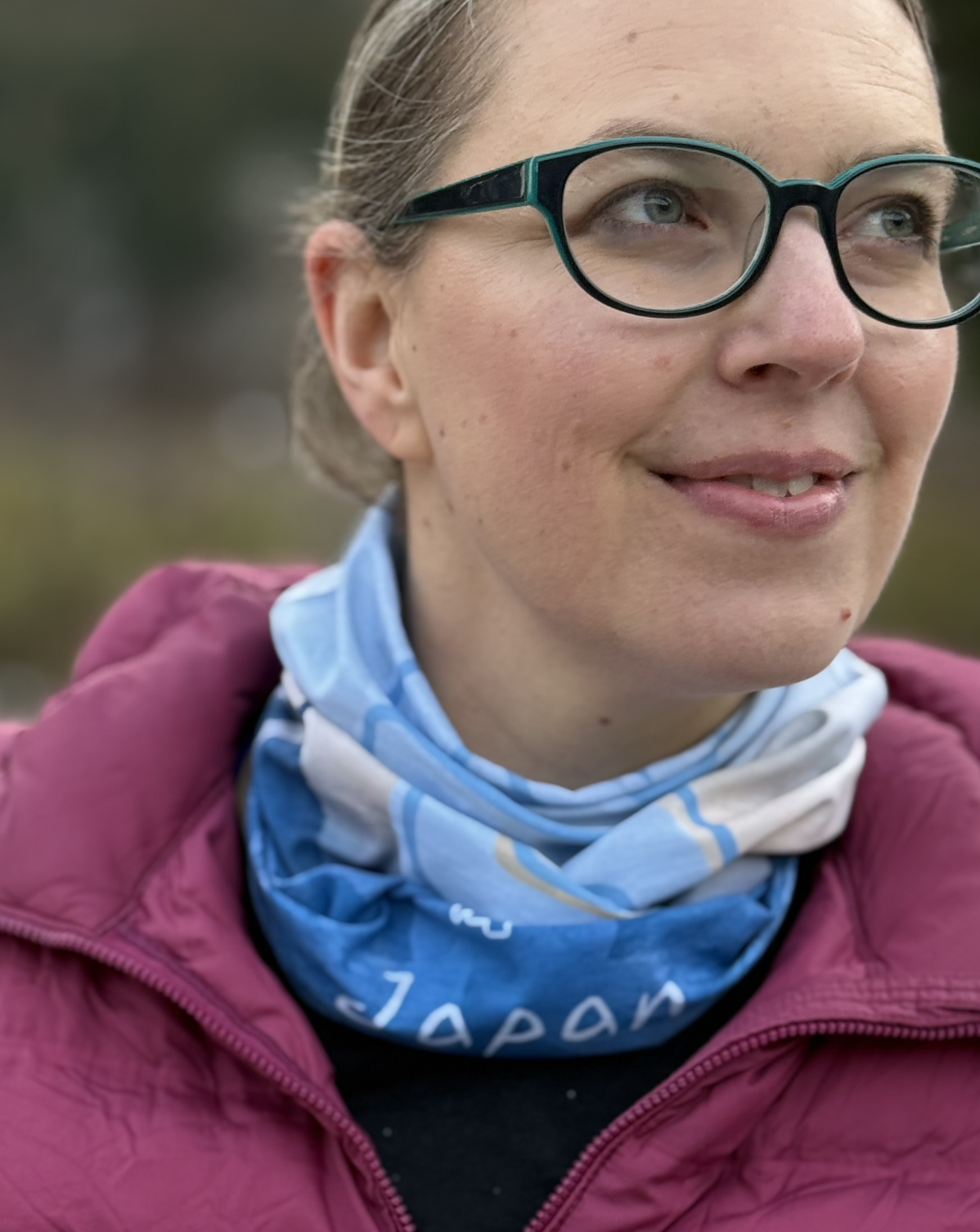 Woman wearing blue and light yellow scarf that reads Japan around her neck.