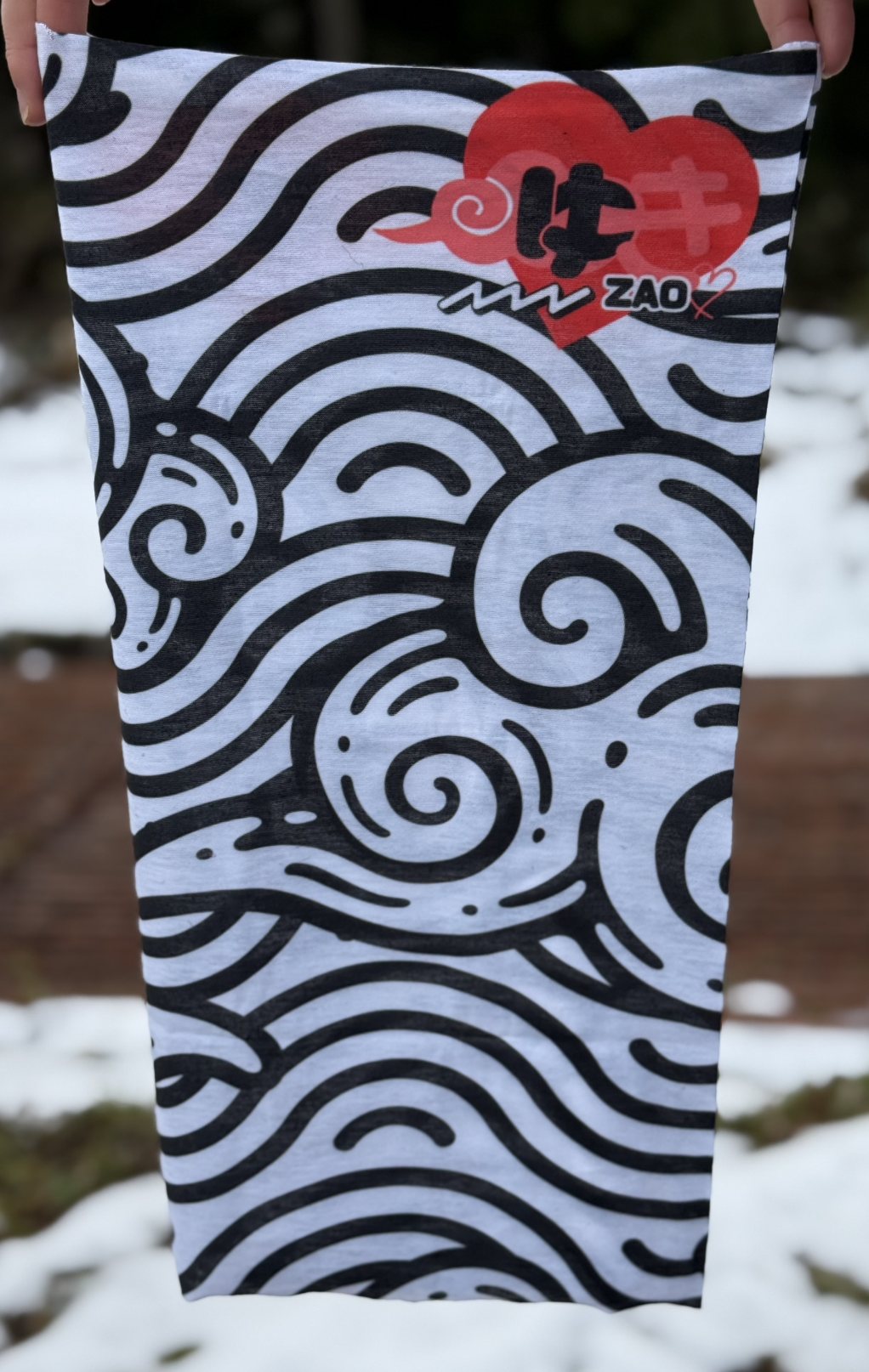 Product image of a rectangular tube ski scarf with a black and red design. Features a red heart and the word yuki or snow and zao, short for Zao onsen.