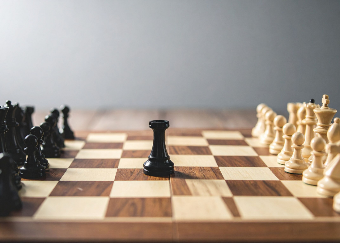 A chessboard with a black pawn in the center, and other black and white chess pieces on each side, ready for a game.