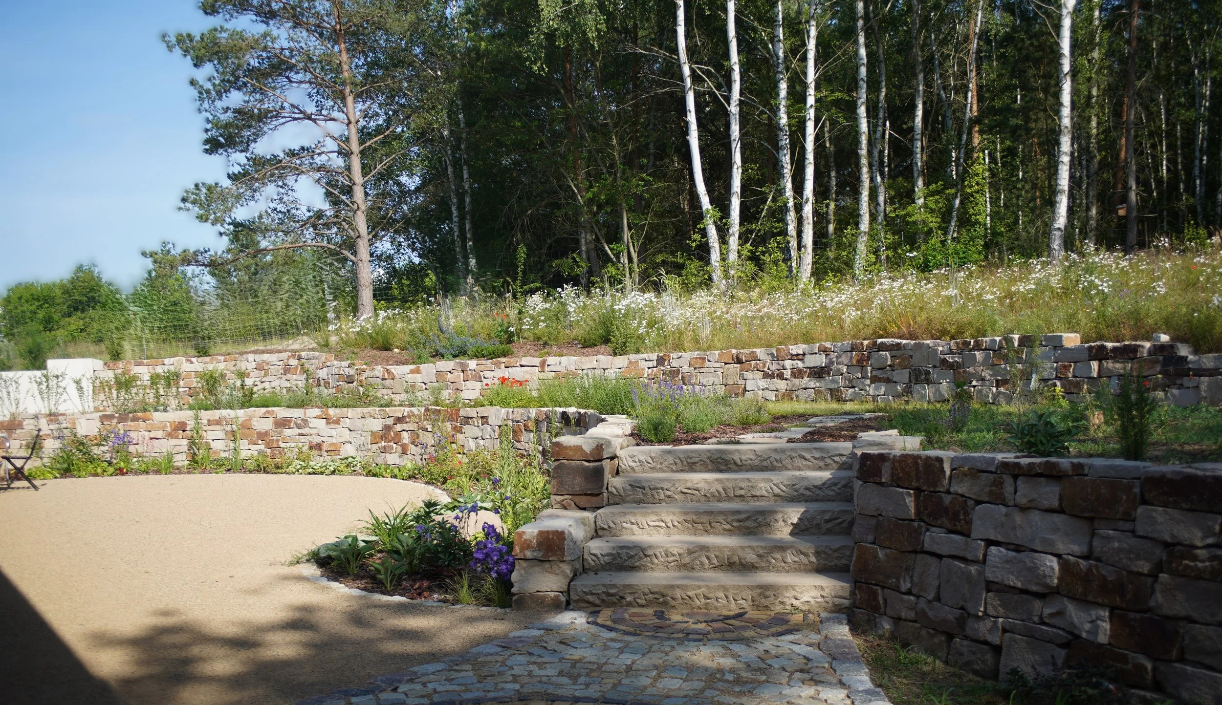 Gartengestaltung mit Terrasse, Trockenmauer und Pflanzung 
