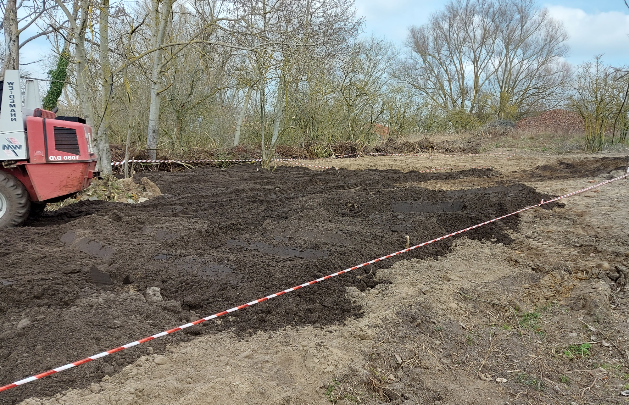 Erdarbeiten, Mutterboden wird mit Bagger aufgebracht