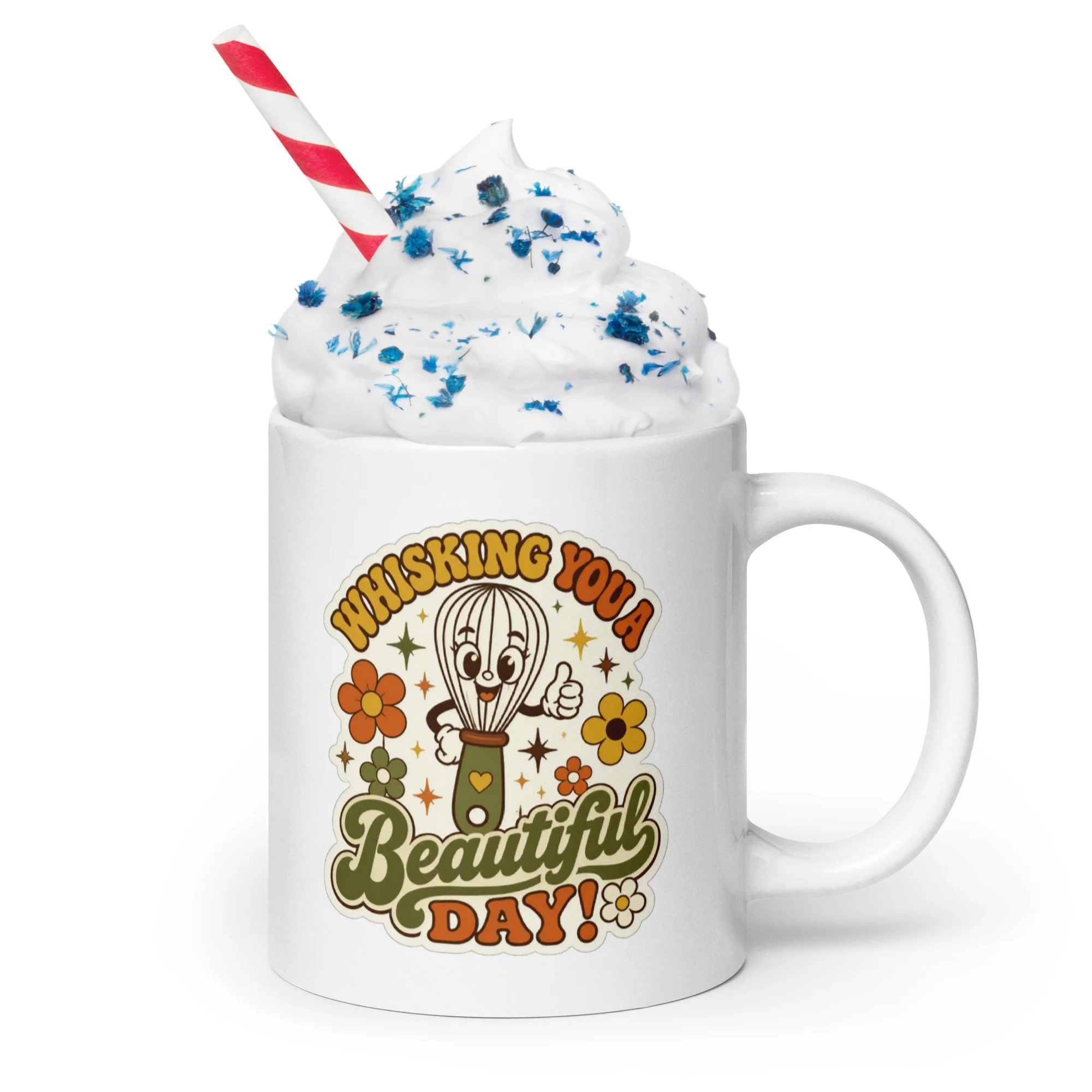 Retro baking mug with whisk and floral design filled with whipped cream and sprinkles, with a striped straw.