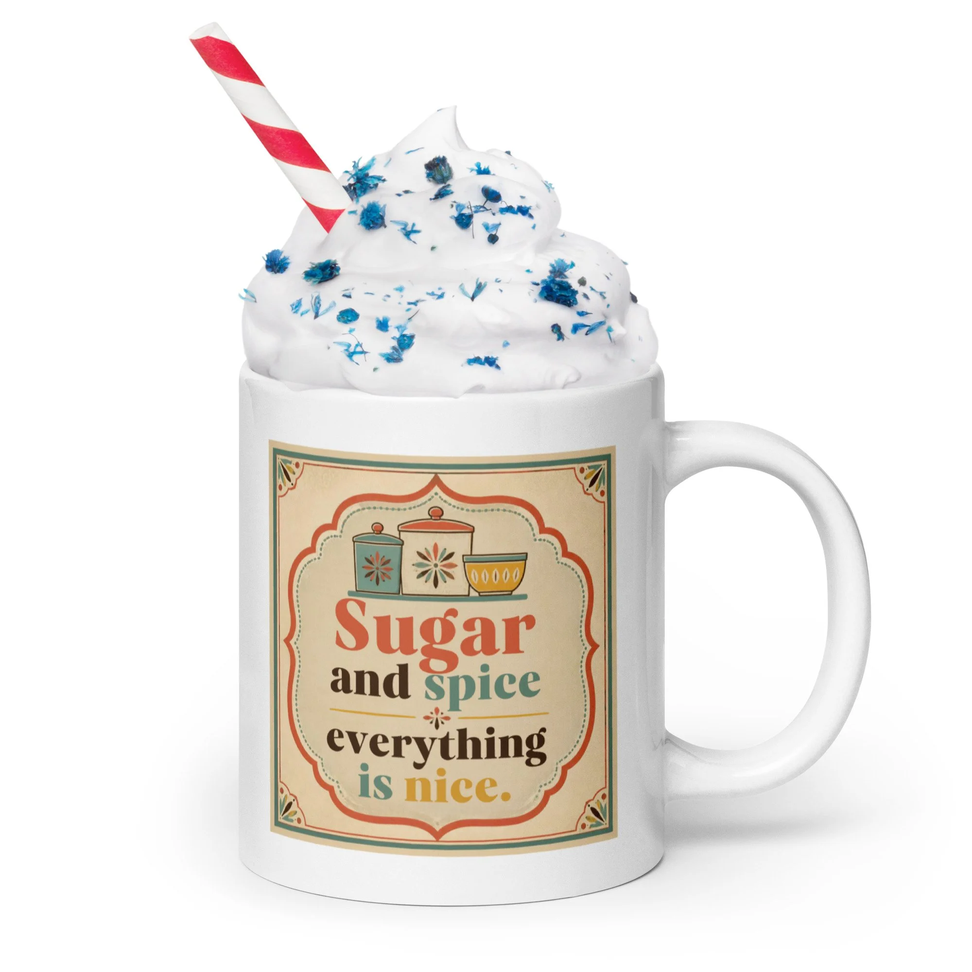 White ceramic mug with “Sugar and spice everything is nice” design shown with whipped cream and sprinkles.