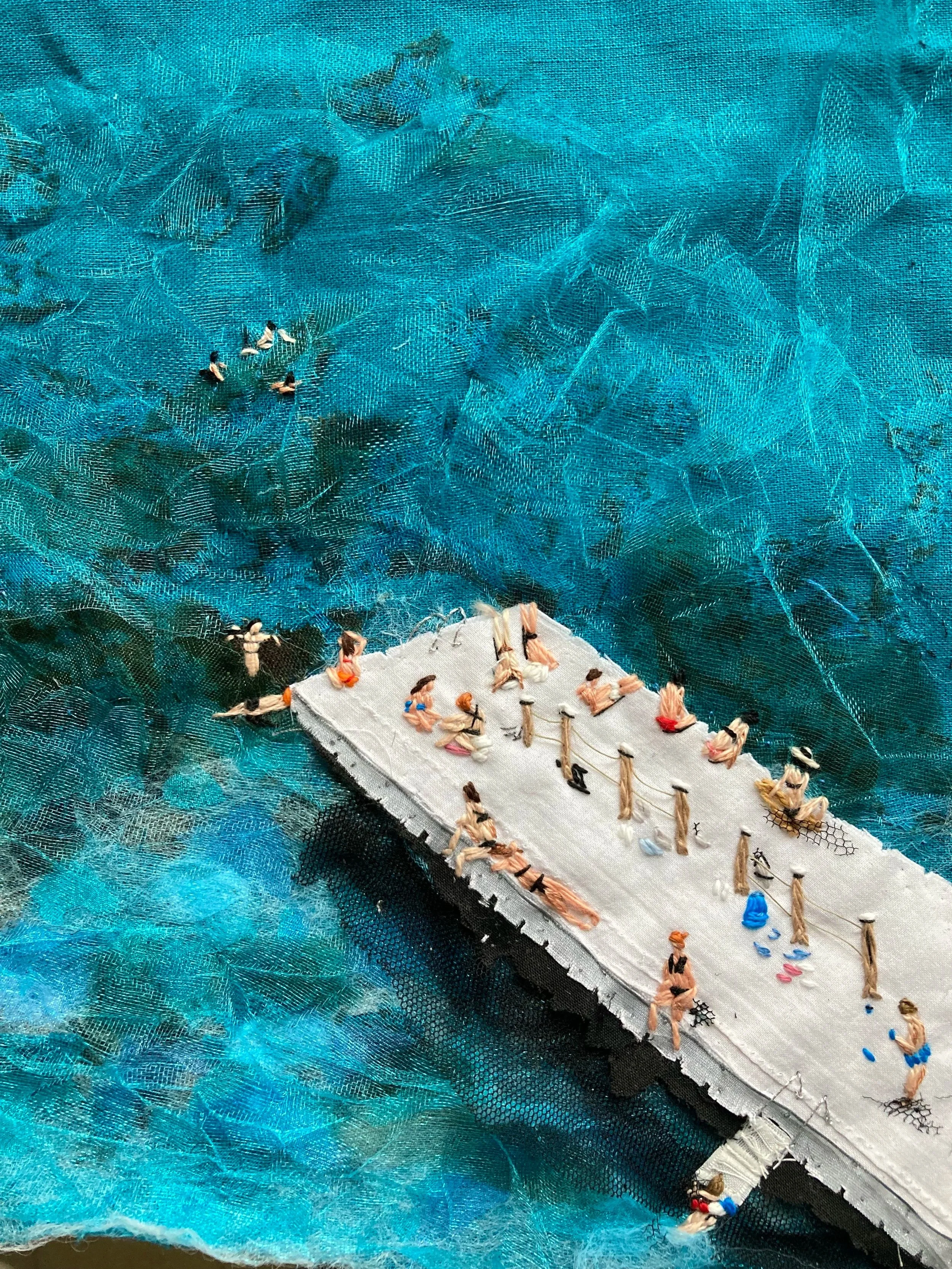 A detailed miniature embroidery artwork depicts a boat filled with tiny embroidered figures, some sitting and some standing, on a textured blue background.