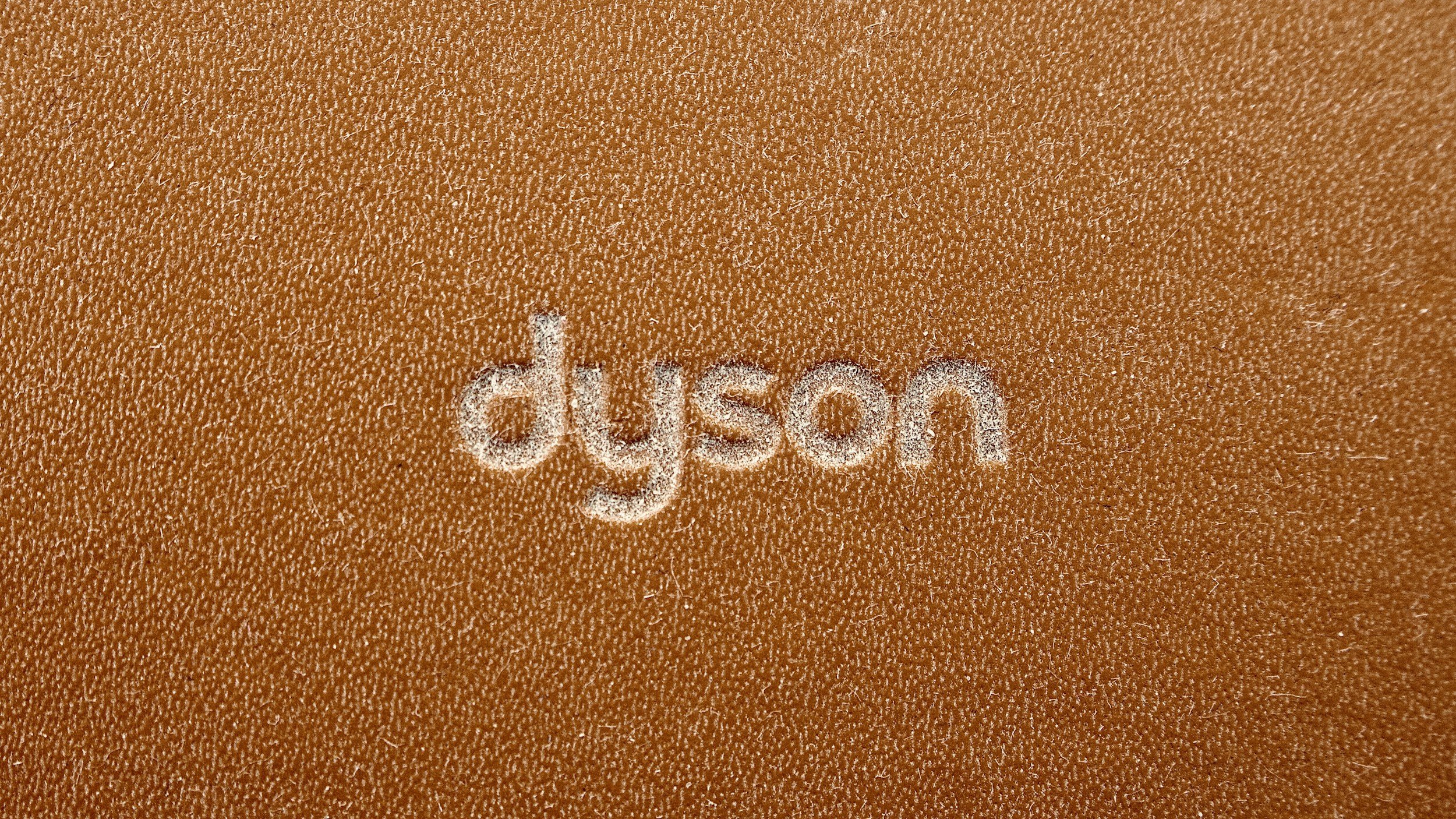 Close-up of a textured orange surface with the word "design" written in white powder.