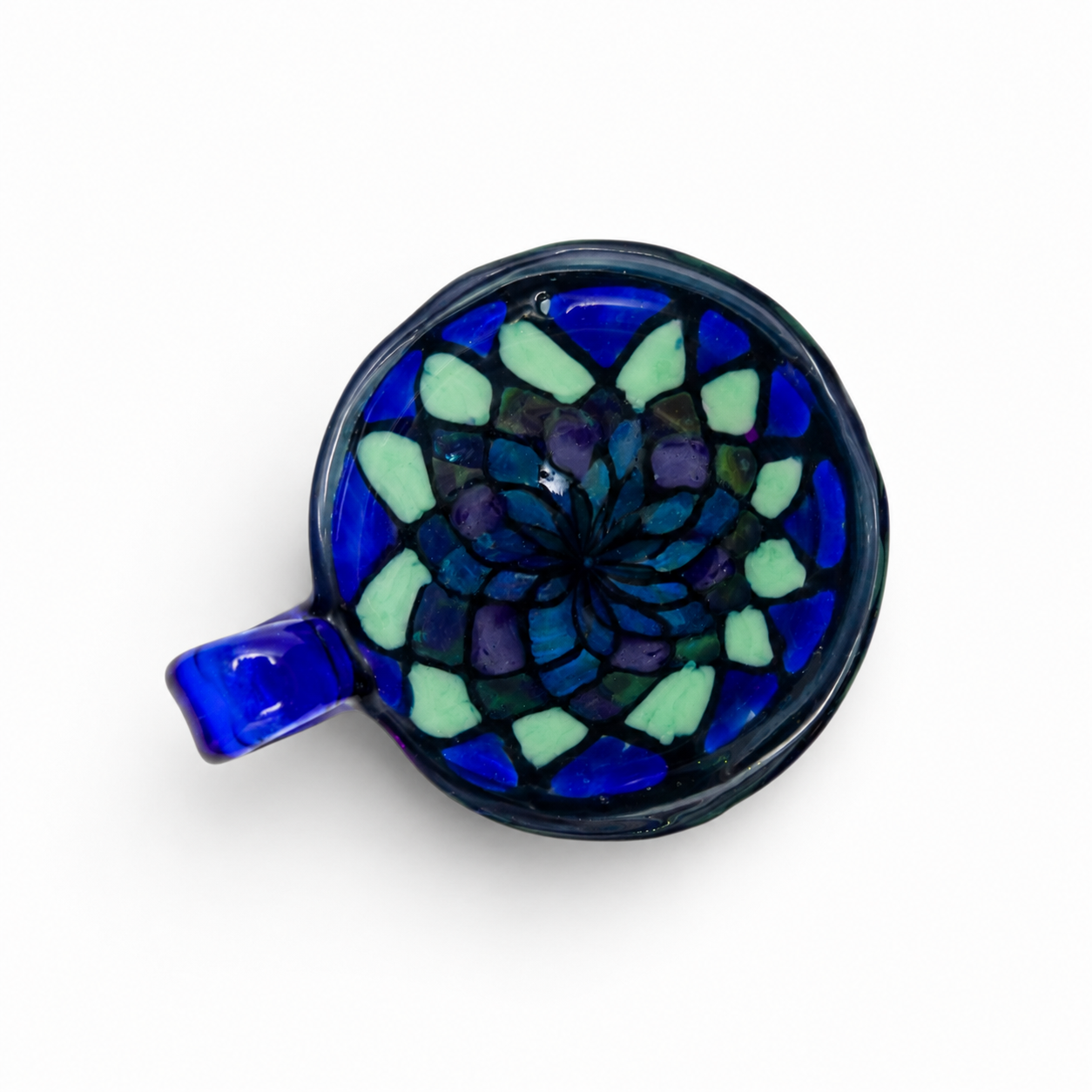 A ceramic mug with a blue and green mosaic pattern inside, viewed from above against a white background.