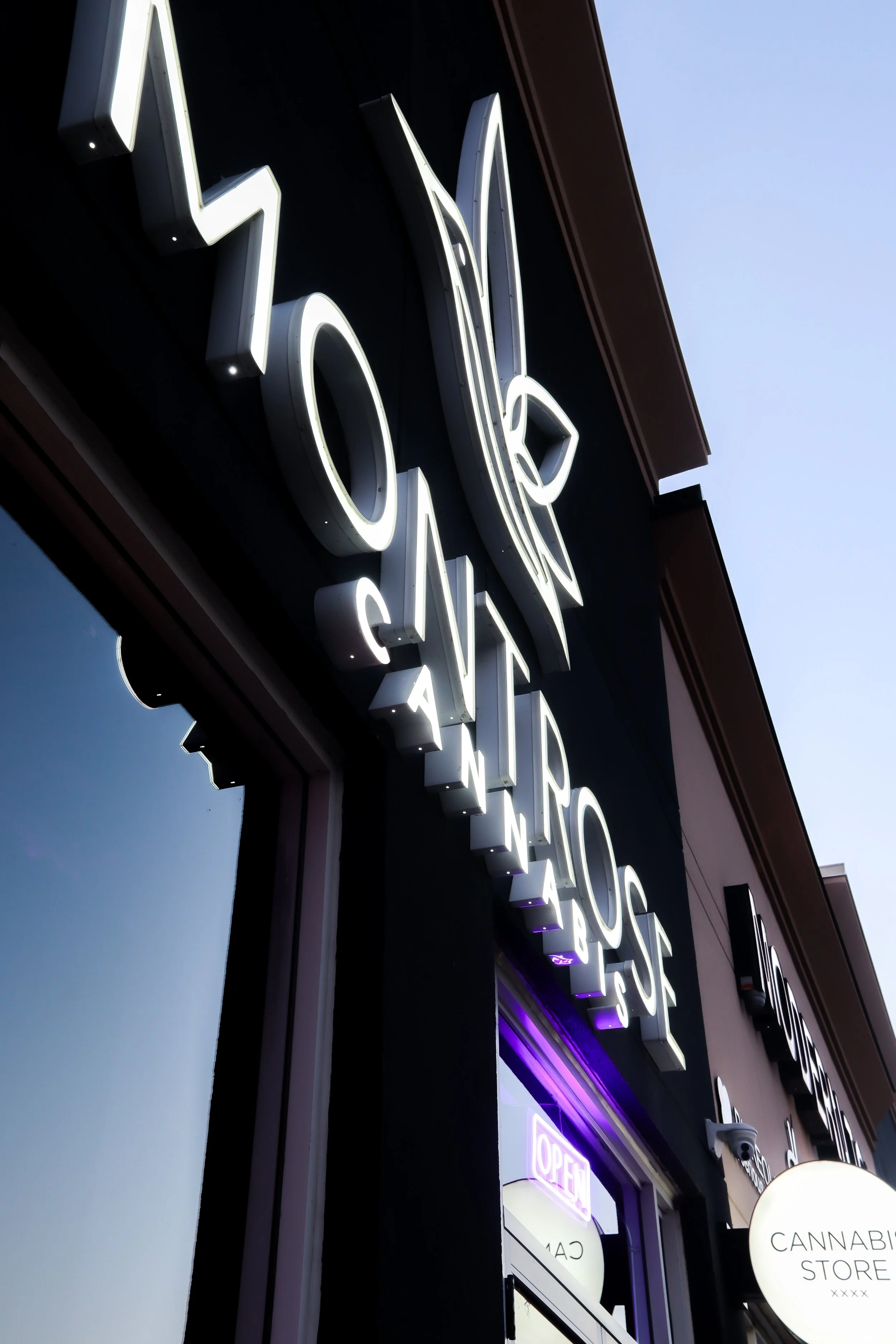 A storefront with illuminated neon signs that say 'CBD' and 'Cannabis Store'.