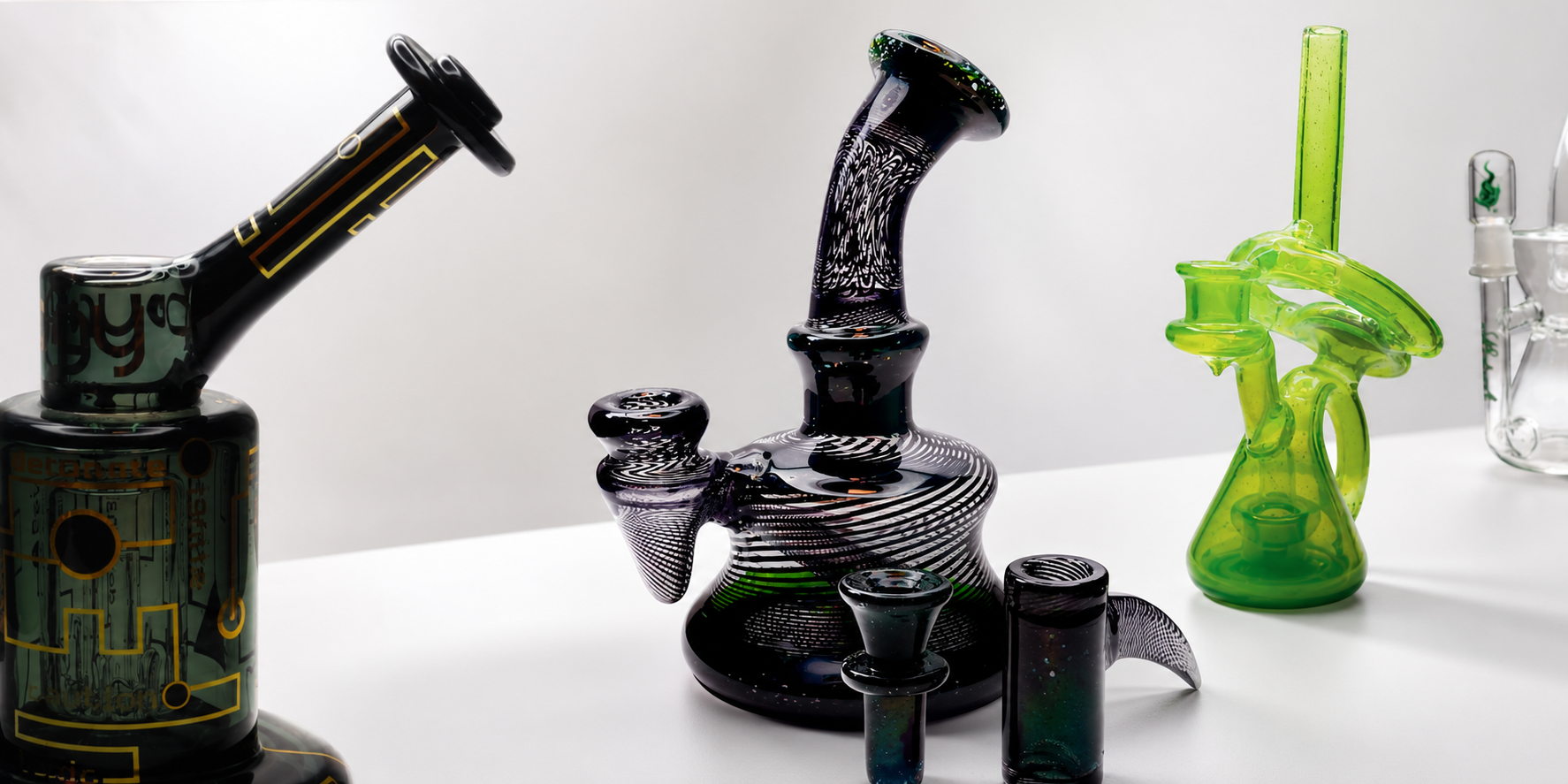 Various colorful glass bongs and pipes displayed on a white surface against a white background.