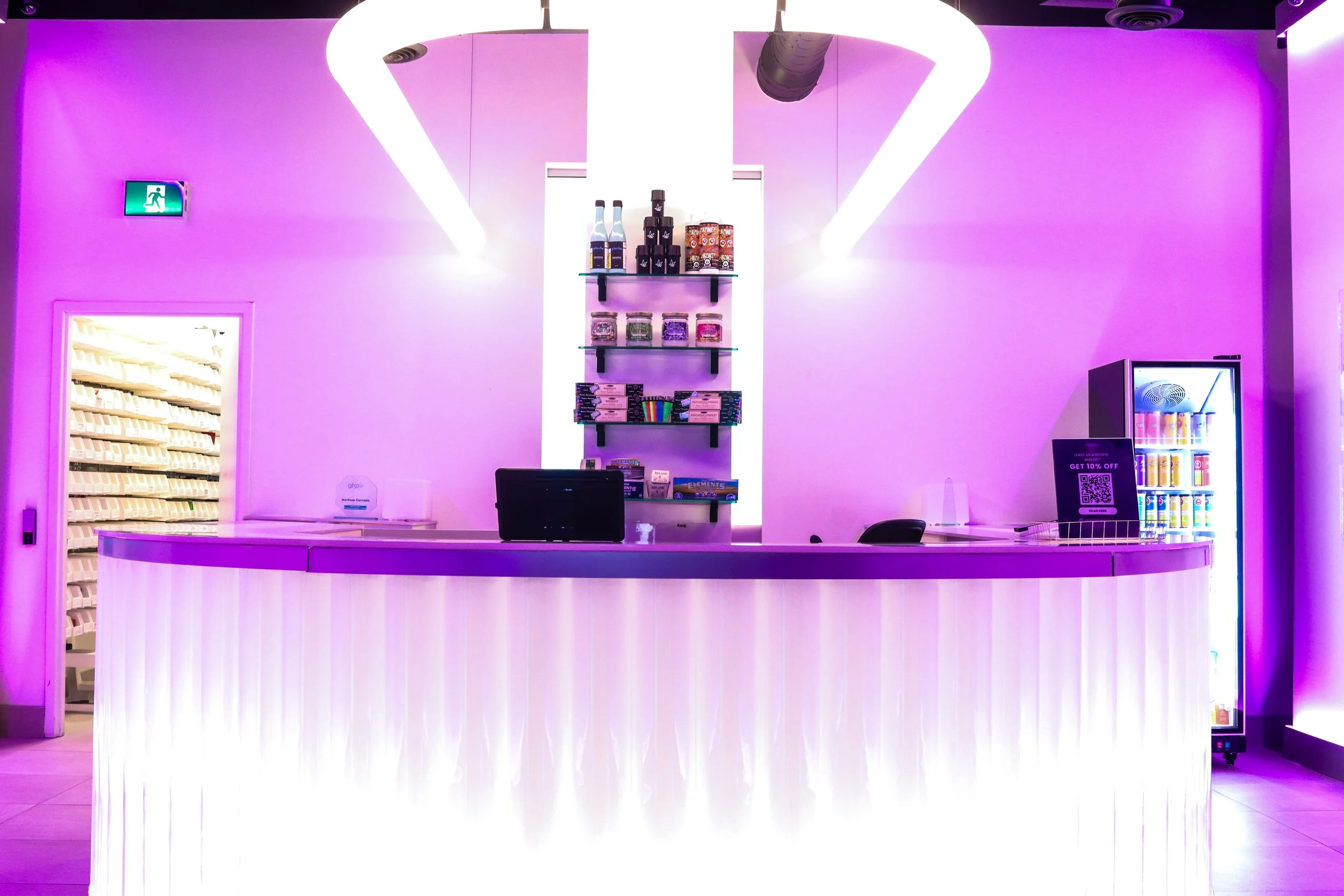 Reception desk with shelves of colorful items and a vending machine on the right, illuminated in purple light.