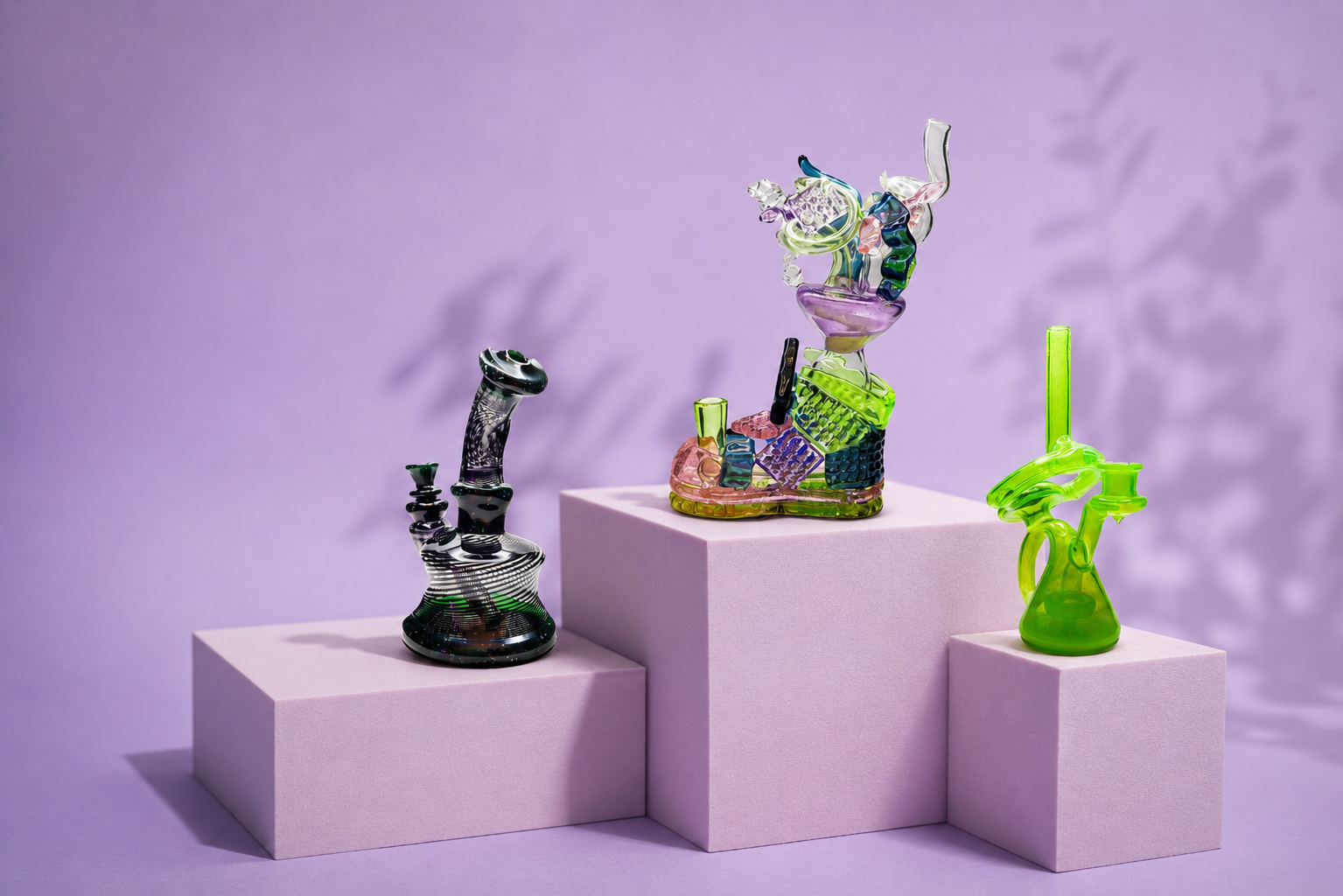 Colorful glass sculptures of abstract shapes on pink display blocks against a purple background.