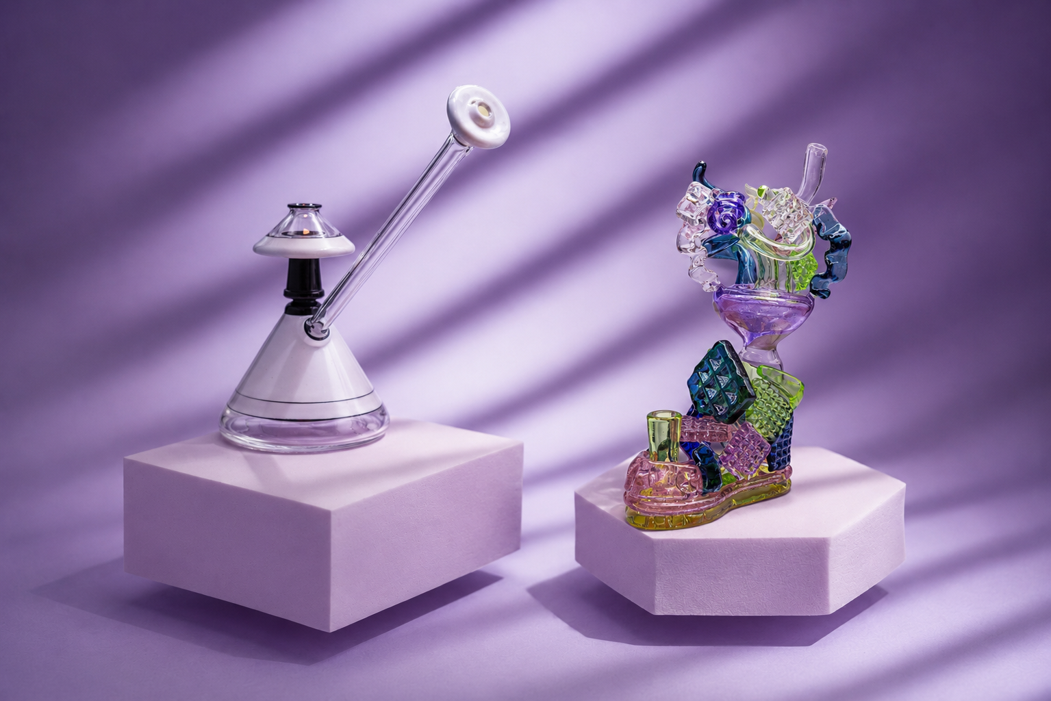 Two glass art sculptures displayed on pink pedestals with purple lighting and shadows.