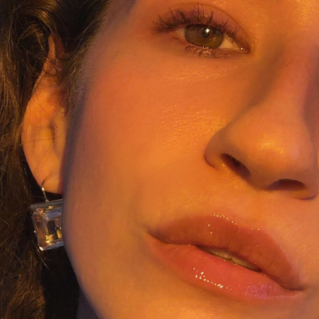 Close-up of a person's face focusing on the left eye, part of the nose, and lips, with a warm lighting.