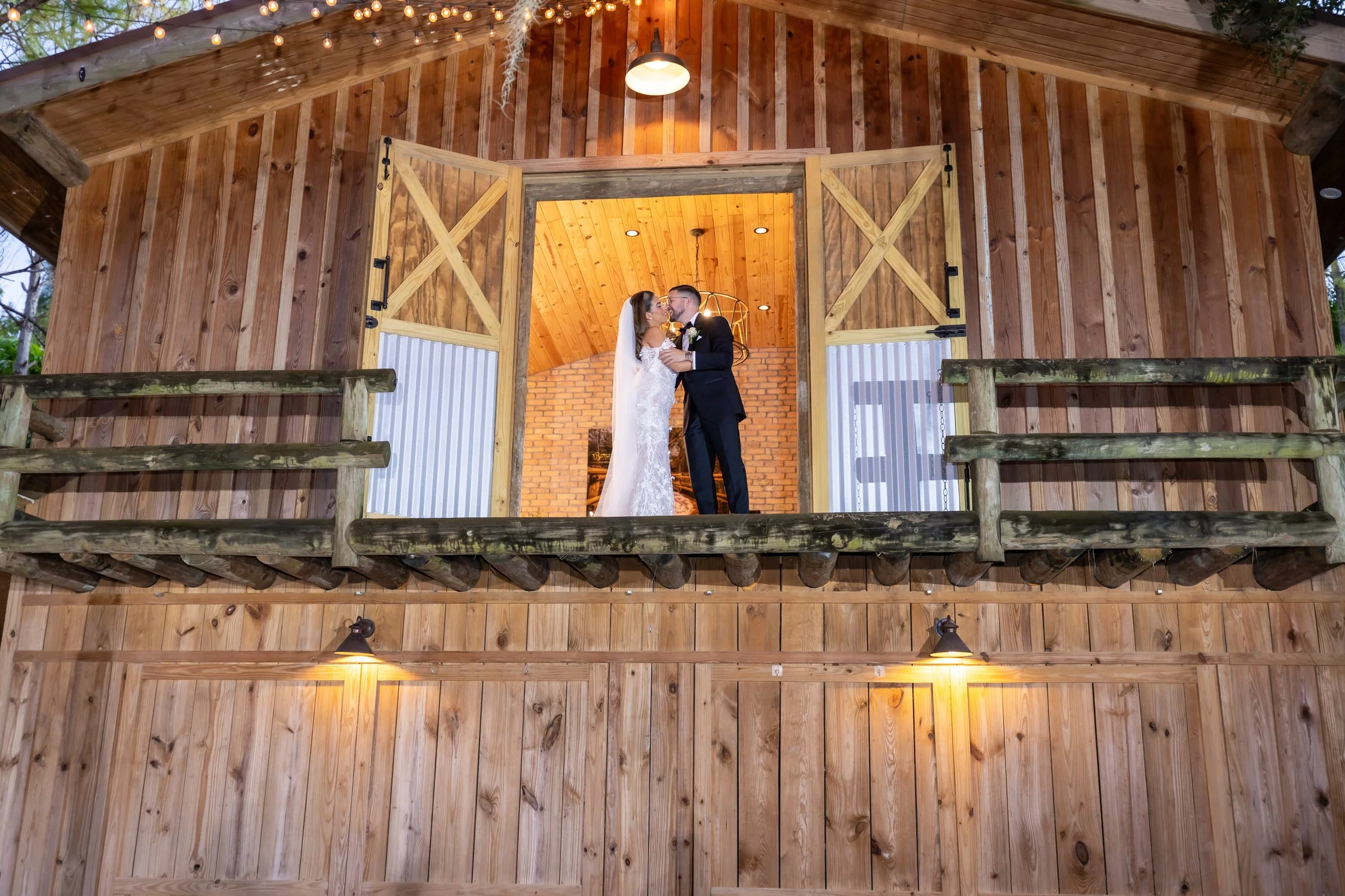 Bride and groom kissing on balcony at The Barn 305 Miami during wedding ceremony with live violin music