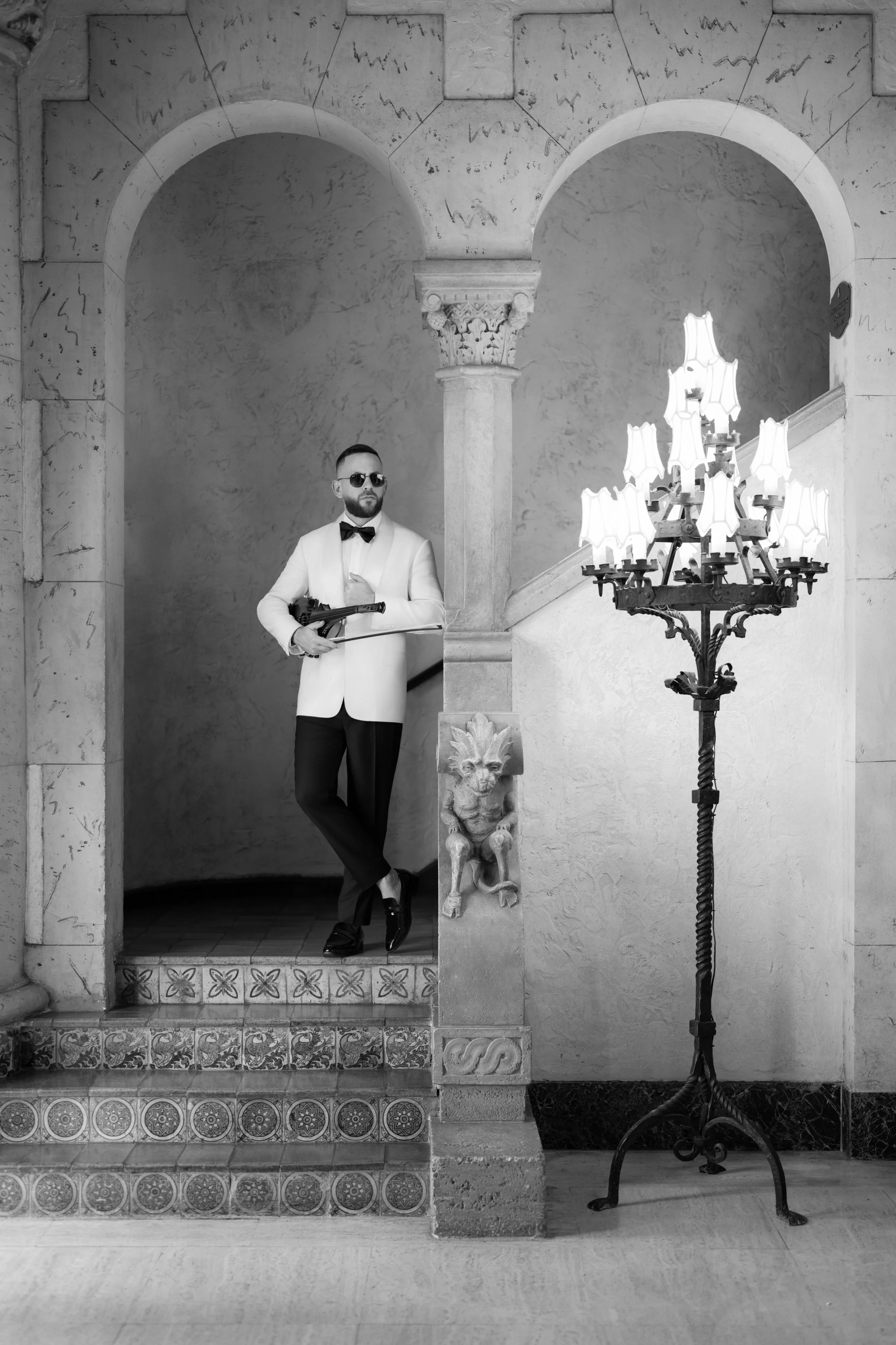 Ronny Moreno performing live violin music in a luxury wedding ceremony venue with elegant arches and classic architecture.