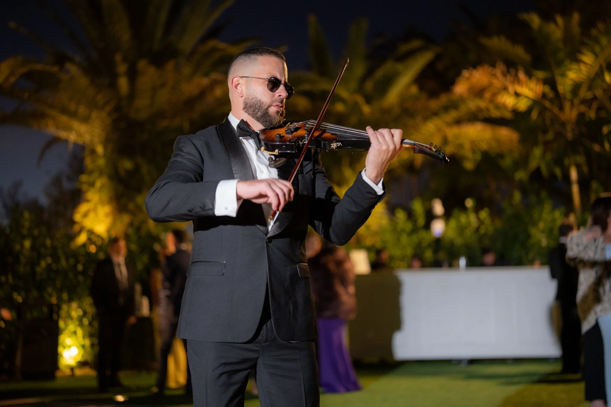 Live violin performance during wedding cocktail hour in Miami with guests in the background