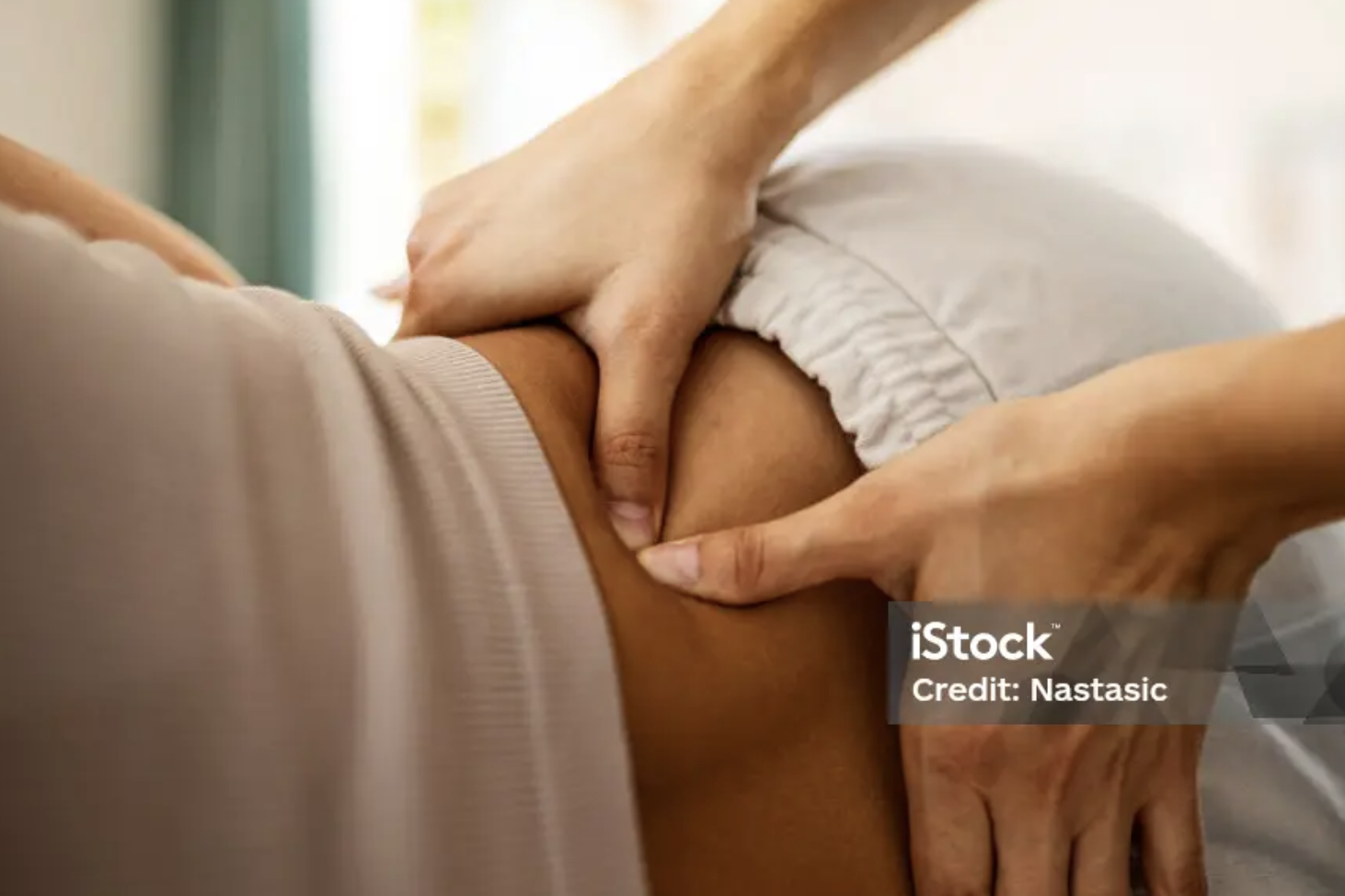 Mains massant la peau d'une personne allongée dans un lit