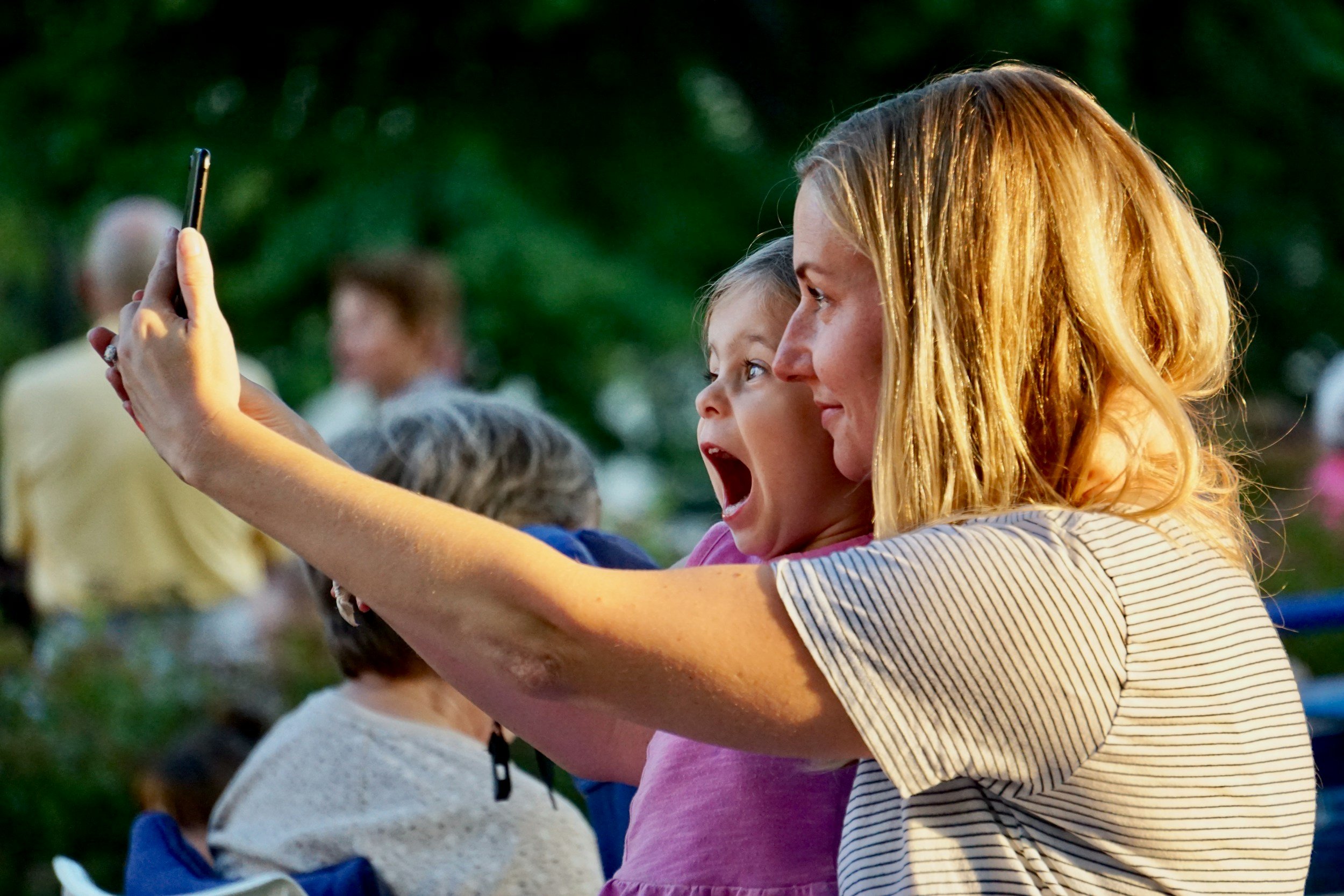 mom and daughter take a selfie while enjoying outdoor summer concert
