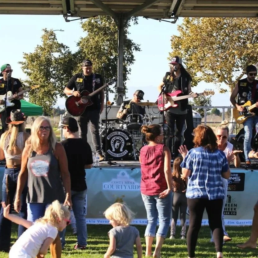 Band performing on an outdoor stage with people dancing and enjoying the music during a summer evening