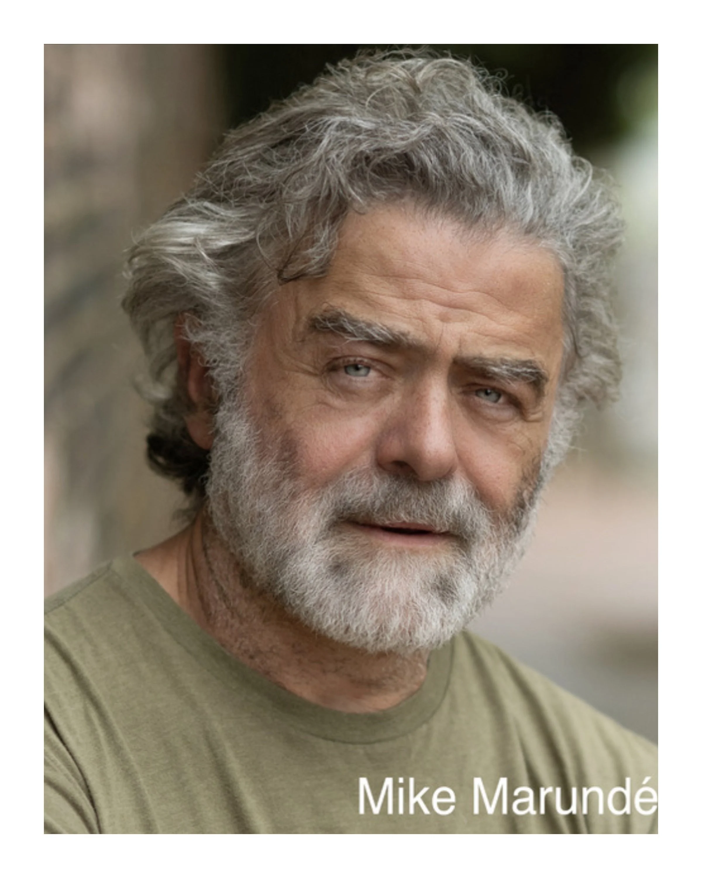 Close-up image of an older man with gray hair and a beard, wearing a green shirt, outdoors with blurred background. The text 'Mike Marundé' is in the bottom right corner.