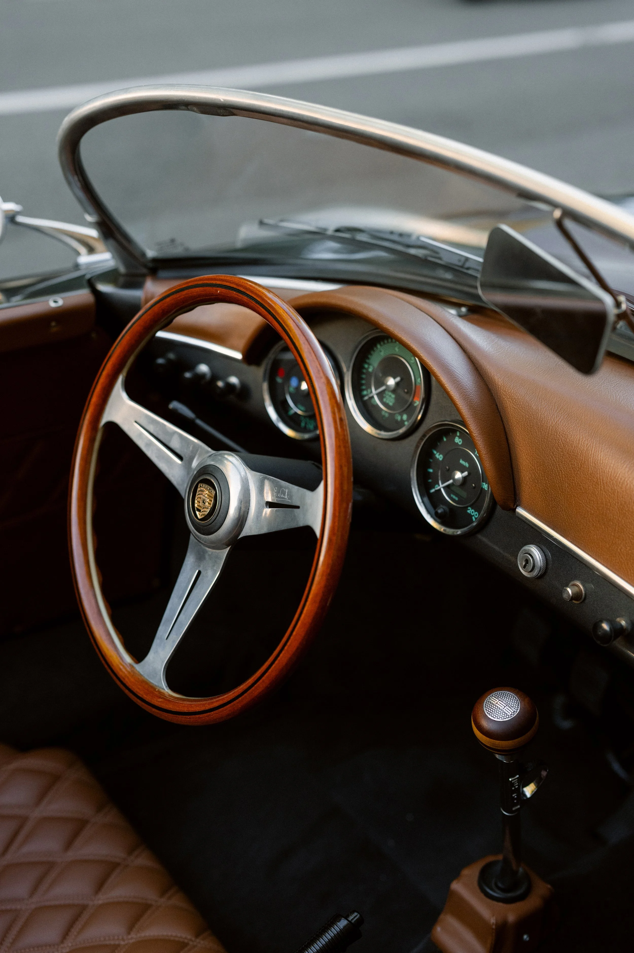 Interior of a vintage car showing a wooden steering wheel, dashboard with dials, and a gear shift.