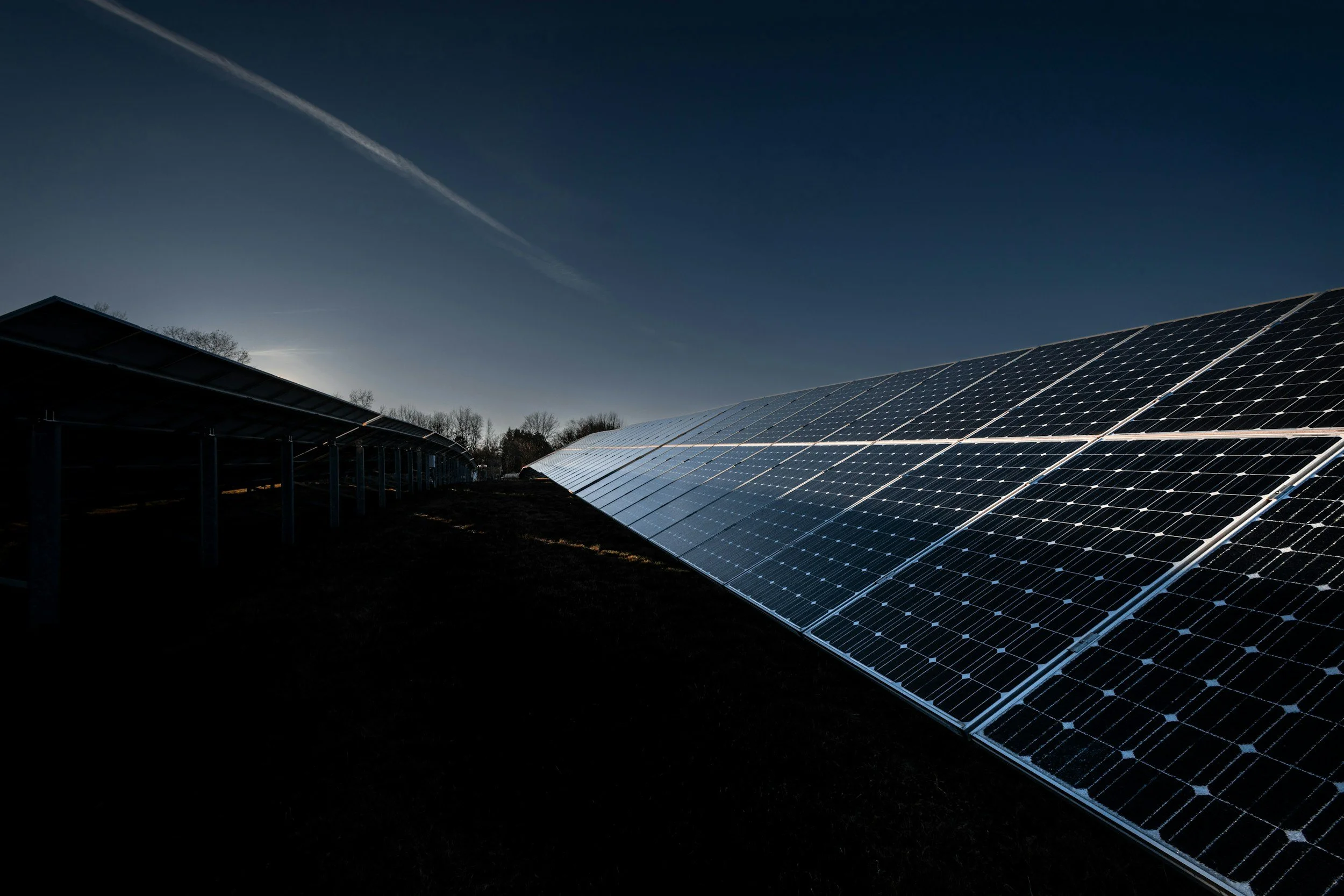 Solar panels arranged in rows outdoors under a clear sky during daytime.