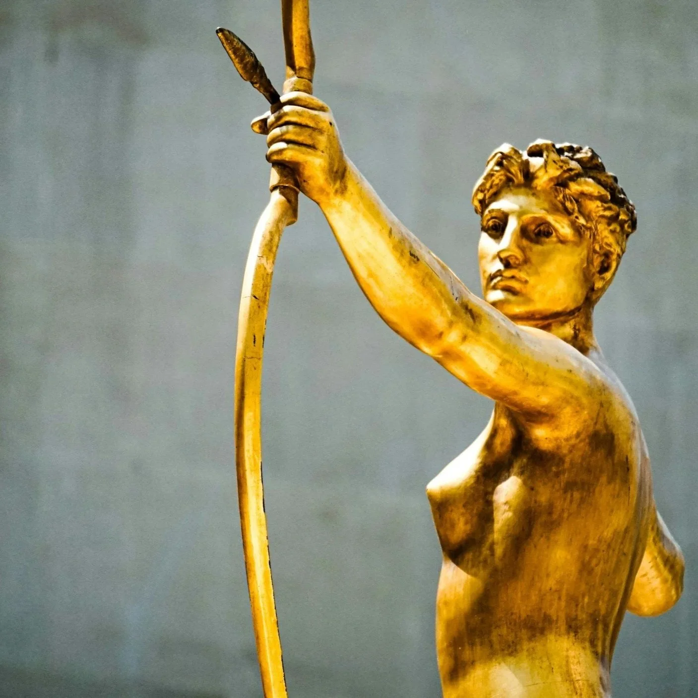 Gold-colored sculpture of a young woman aiming a bow and arrow.